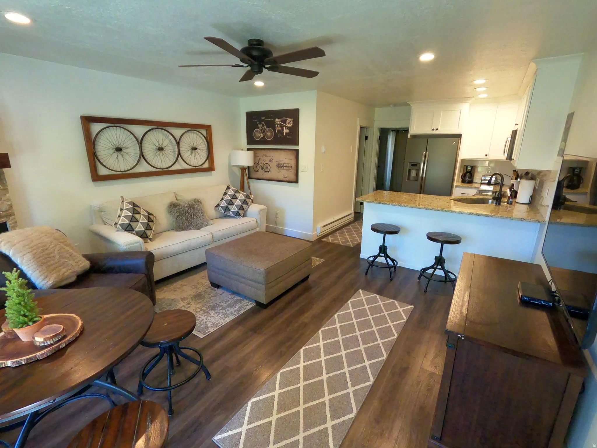 Living area with dark wood-type flooring, recessed lighting, baseboard heating, and a ceiling fan