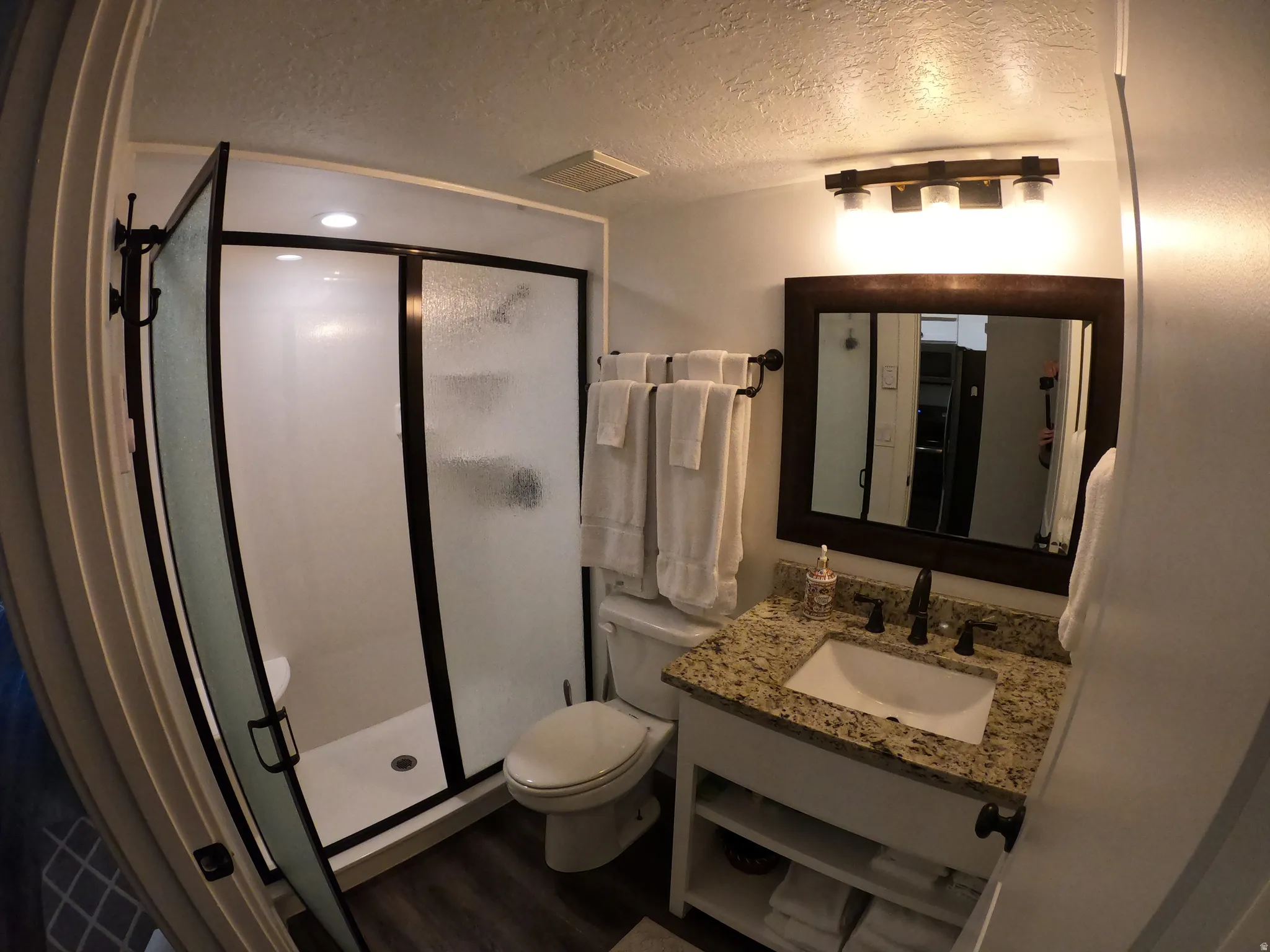 Bathroom featuring a shower stall, a textured ceiling, vanity, and dark wood finished floors
