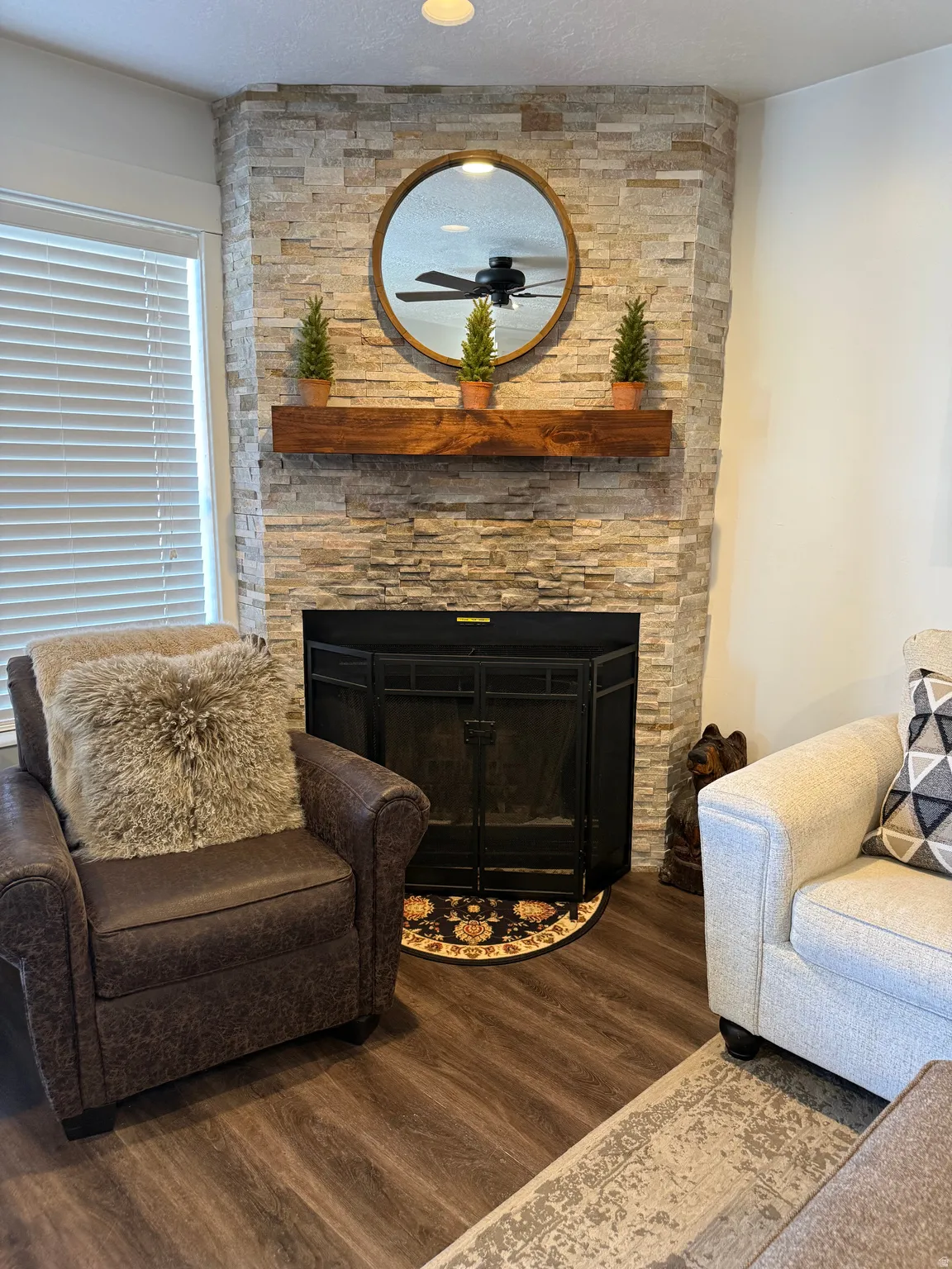 Sitting room featuring a stone fireplace and wood finished floors