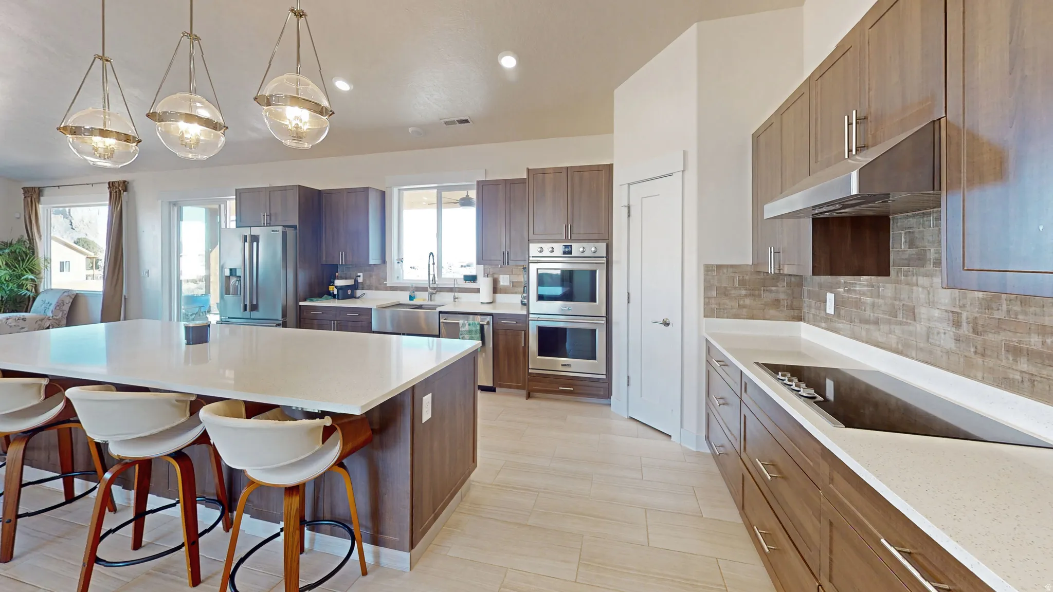 Kitchen with hanging light fixtures, backsplash, a kitchen island, stainless steel appliances, and a kitchen bar