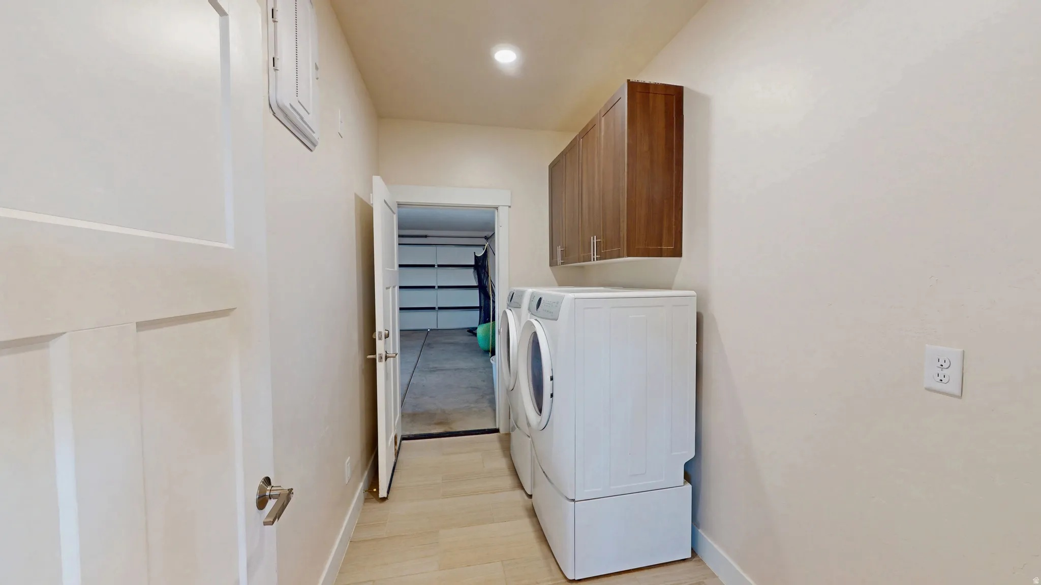 Washroom featuring cabinet space, washer and clothes dryer, and light wood-type flooring