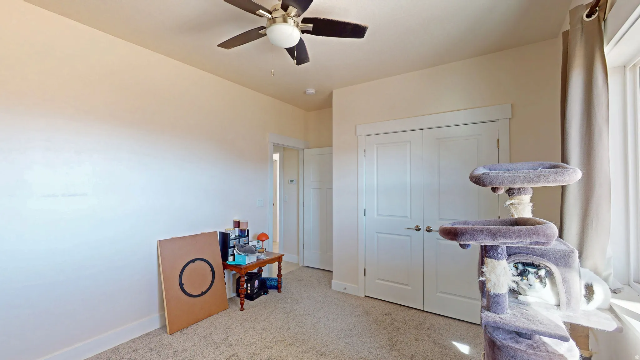Bedroom featuring light carpet, a ceiling fan, and a closet