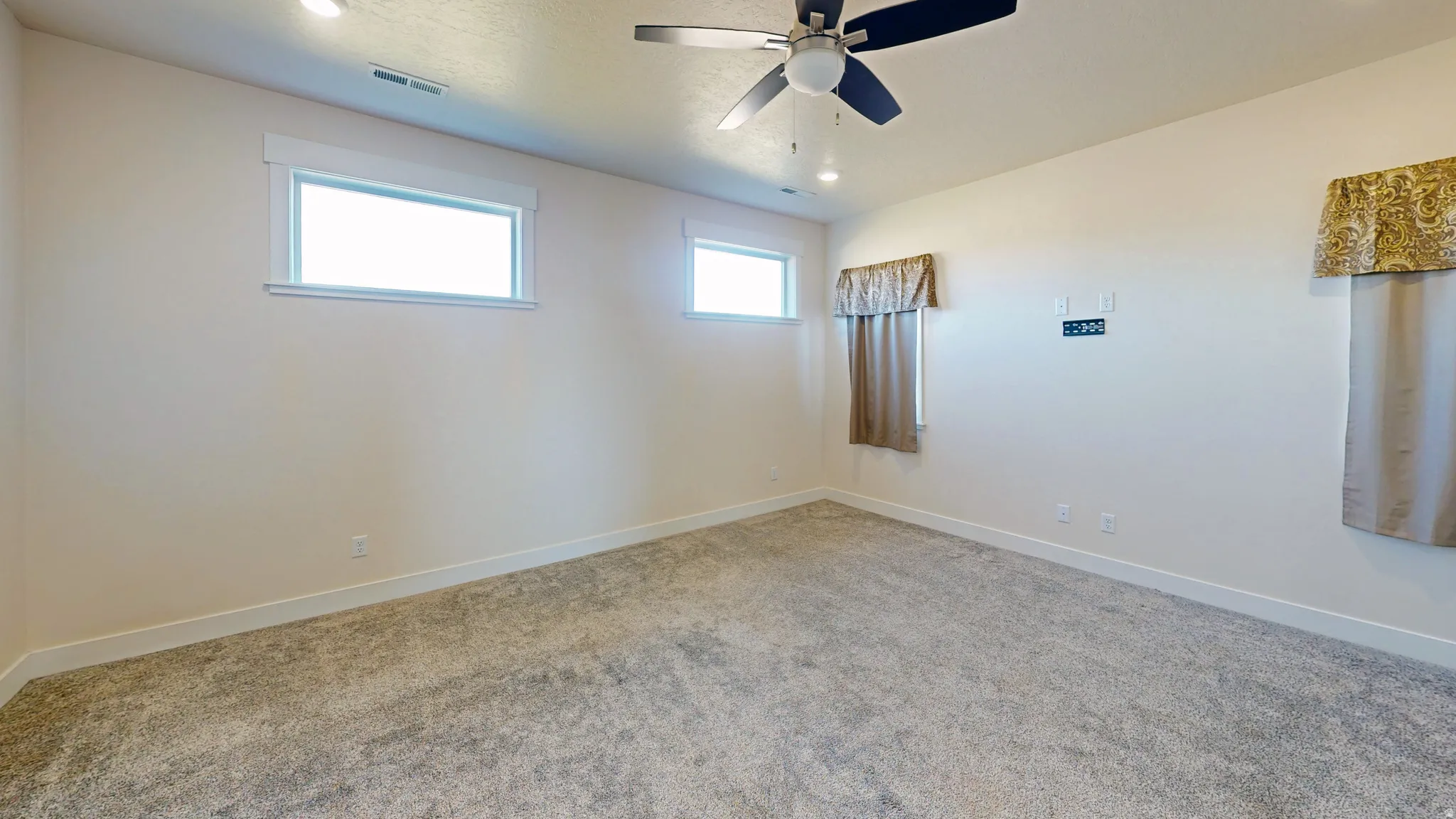 Empty room with carpet floors and ceiling fan