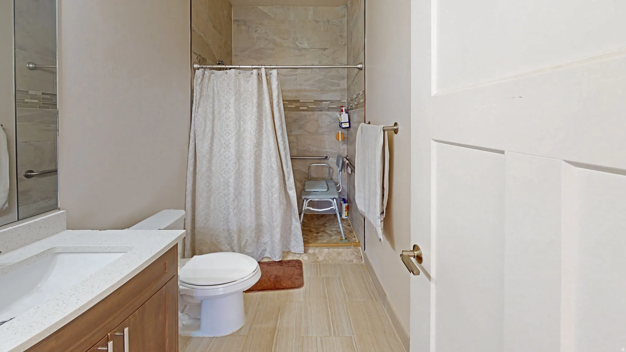 Full bath featuring a tile shower and vanity