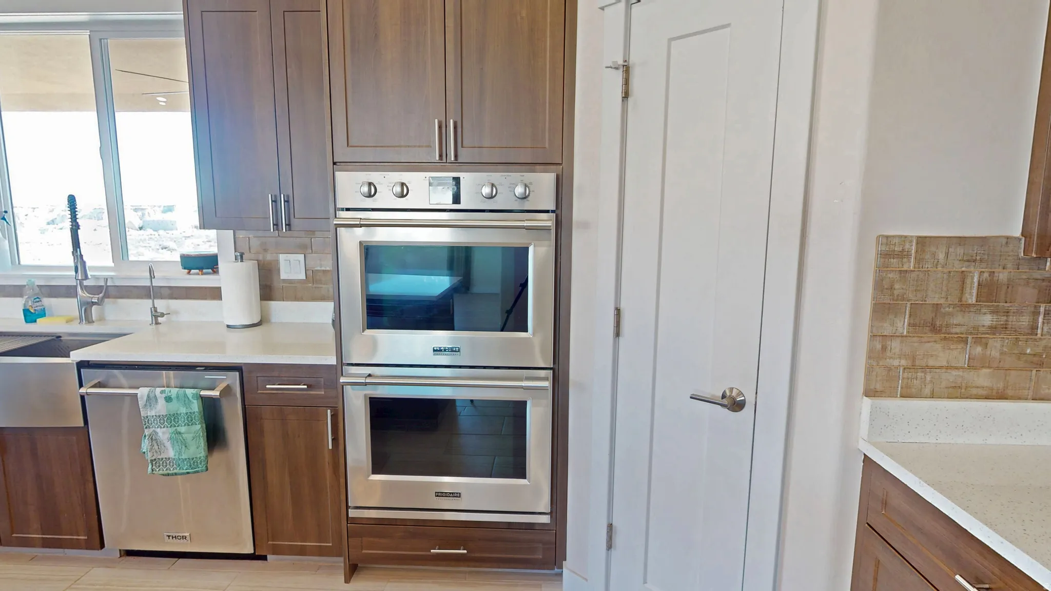 Kitchen featuring appliances with stainless steel finishes, decorative backsplash, and light stone countertops