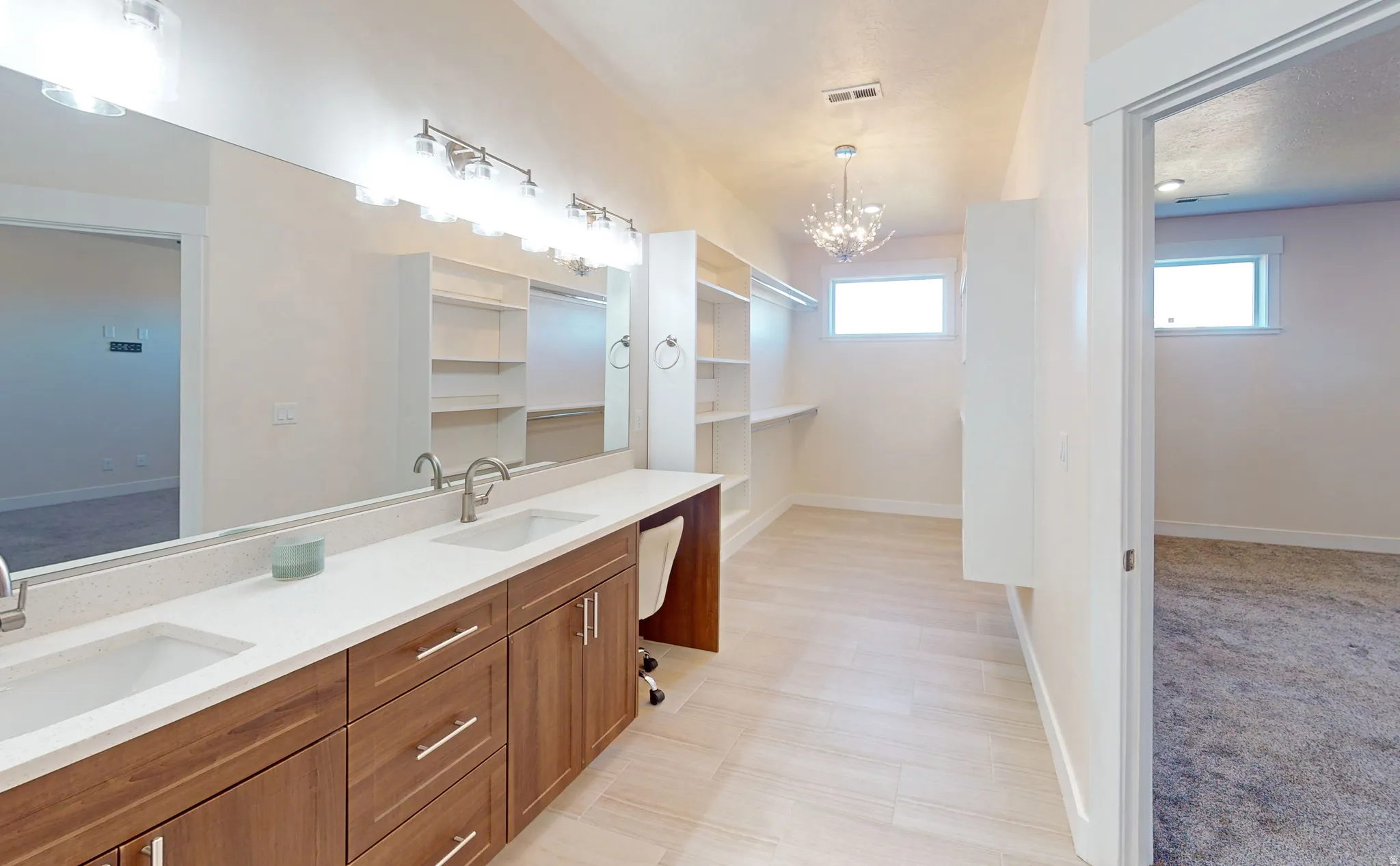 Bathroom featuring double vanity, a chandelier, and a spacious closet