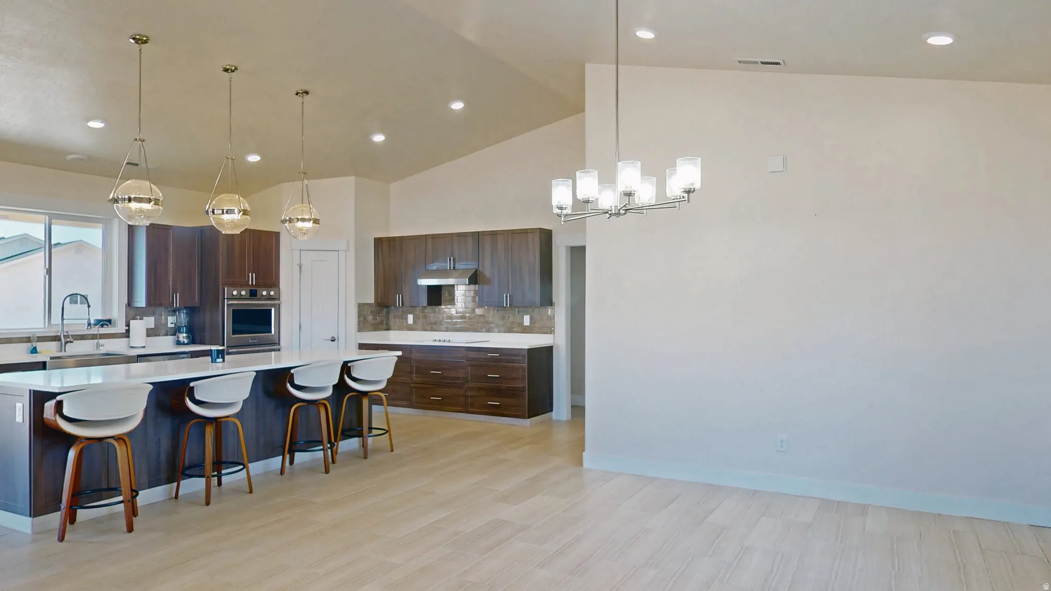 Kitchen featuring a kitchen breakfast bar, a spacious island, pendant lighting, decorative backsplash, and light wood-style flooring