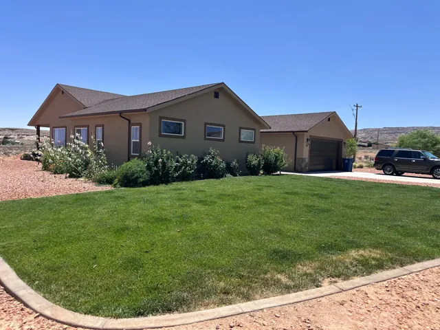 Ranch-style house featuring stucco siding, driveway, and a front yard