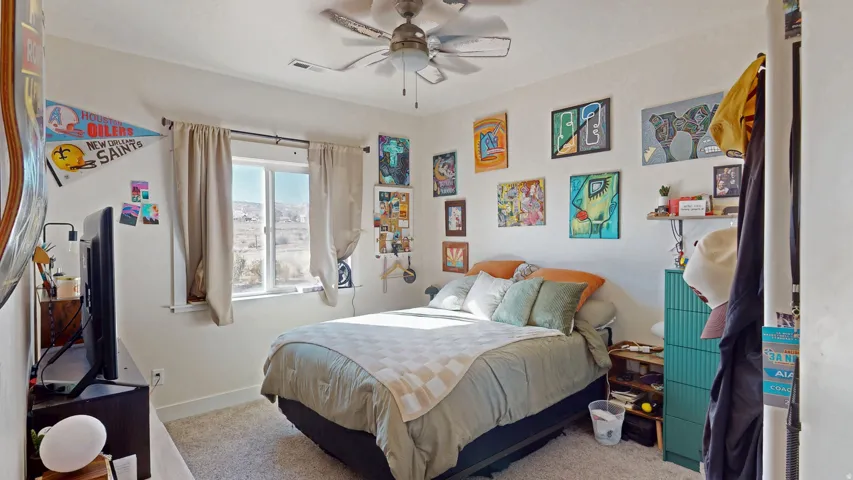 Carpeted bedroom with a ceiling fan and baseboards