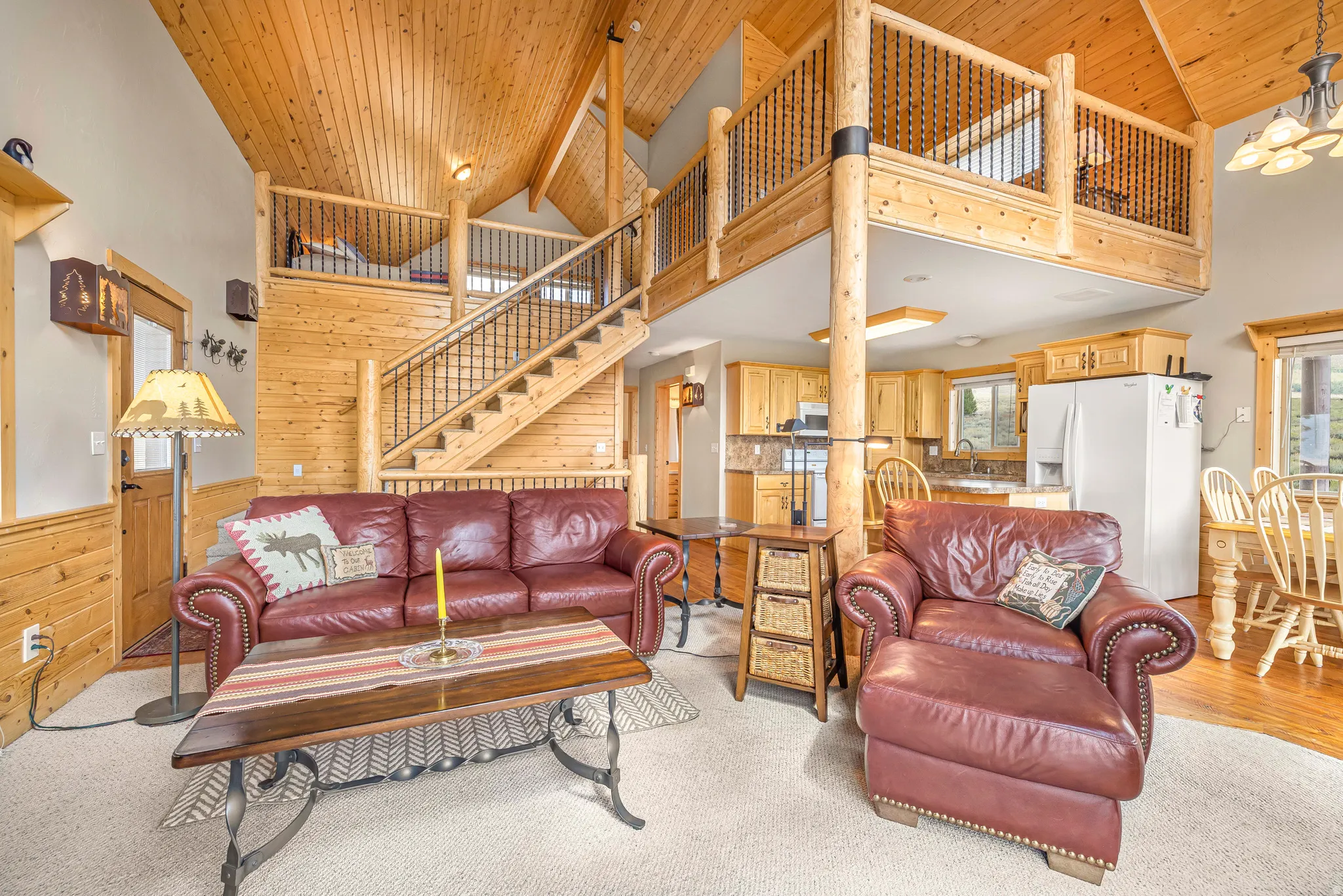 Living room featuring wood walls, high vaulted ceiling, wood ceiling, a chandelier, and stairs