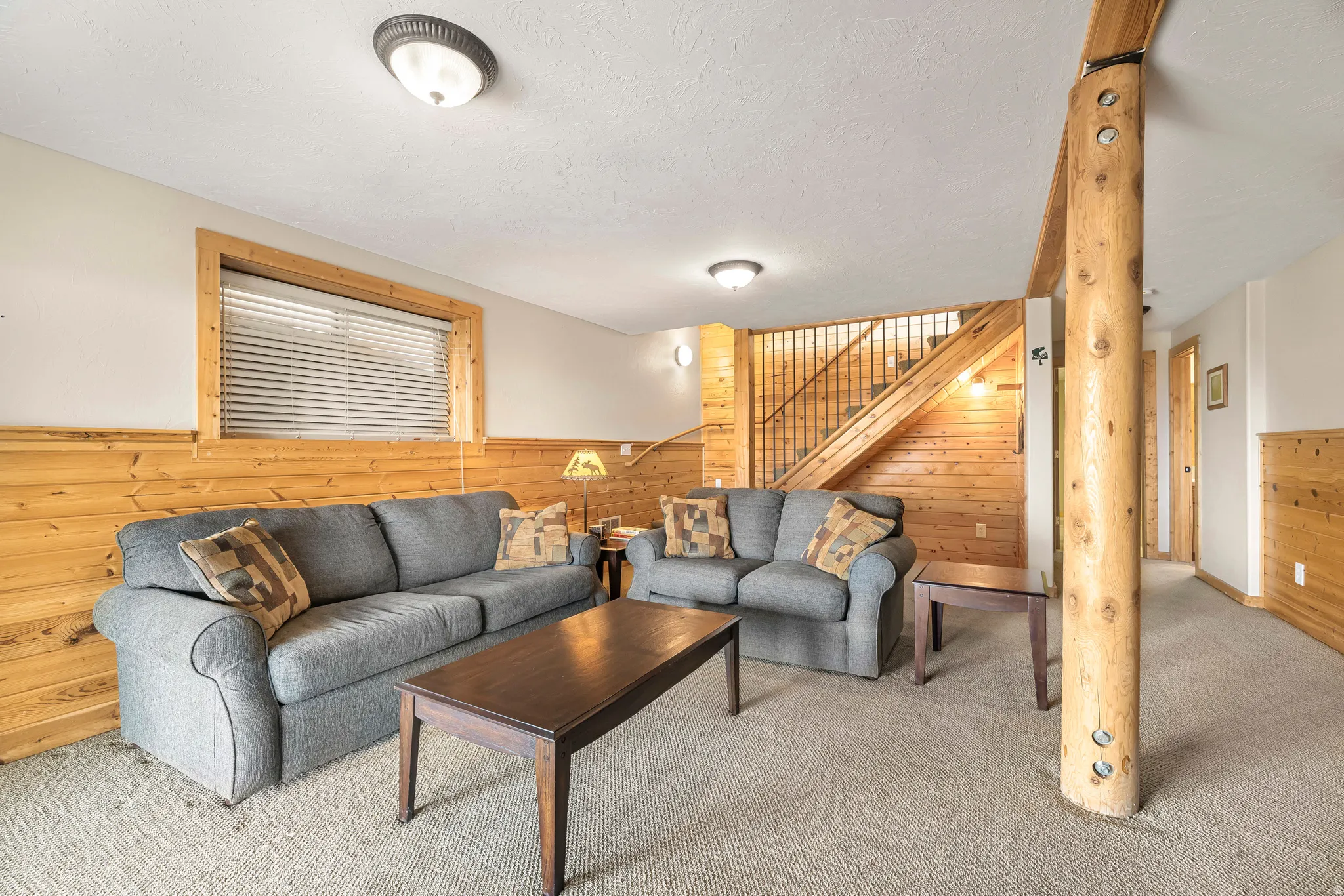 Living area with wood walls, carpet flooring, a textured ceiling, a wainscoted wall, and stairway