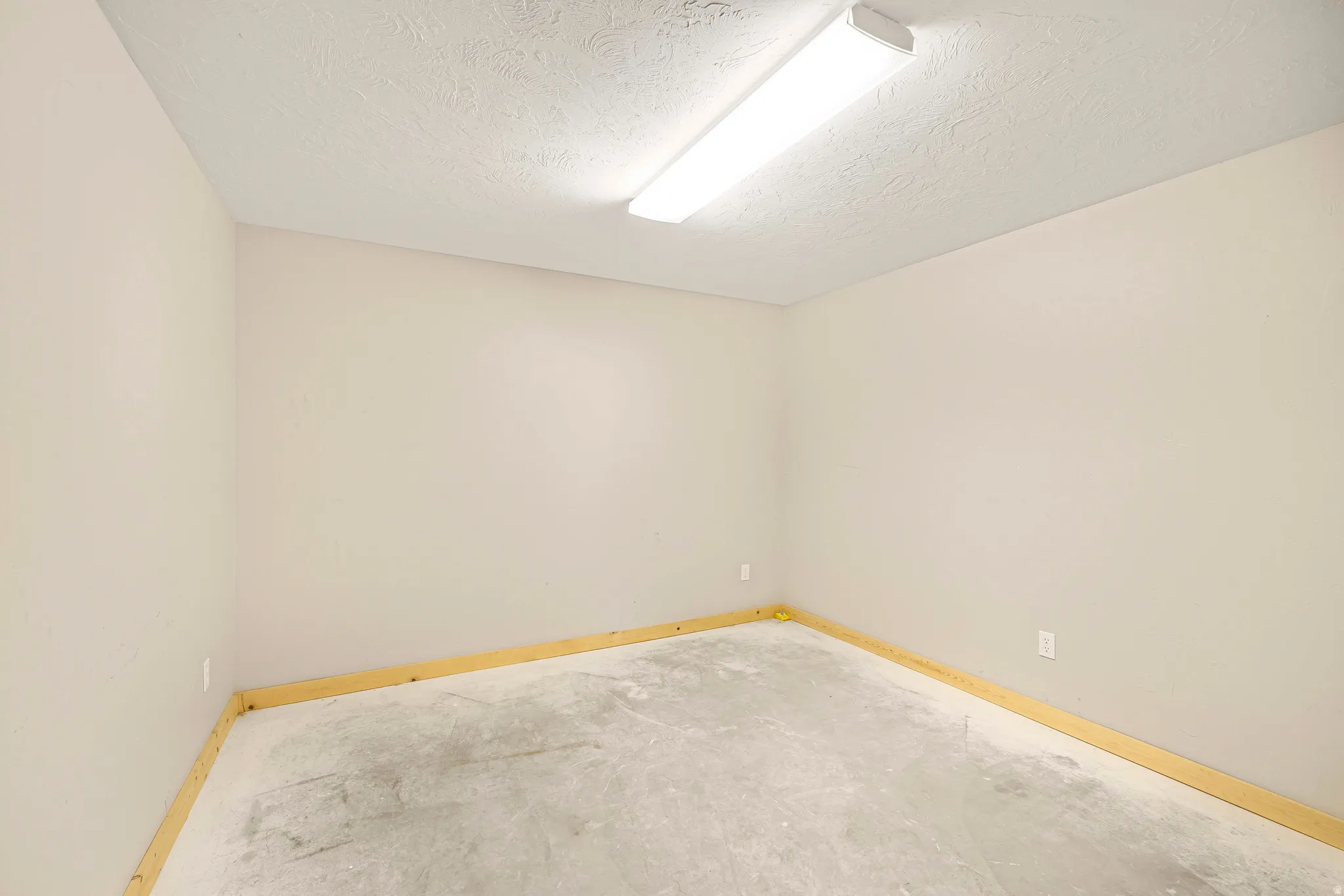 Unfurnished room with baseboards and a textured ceiling