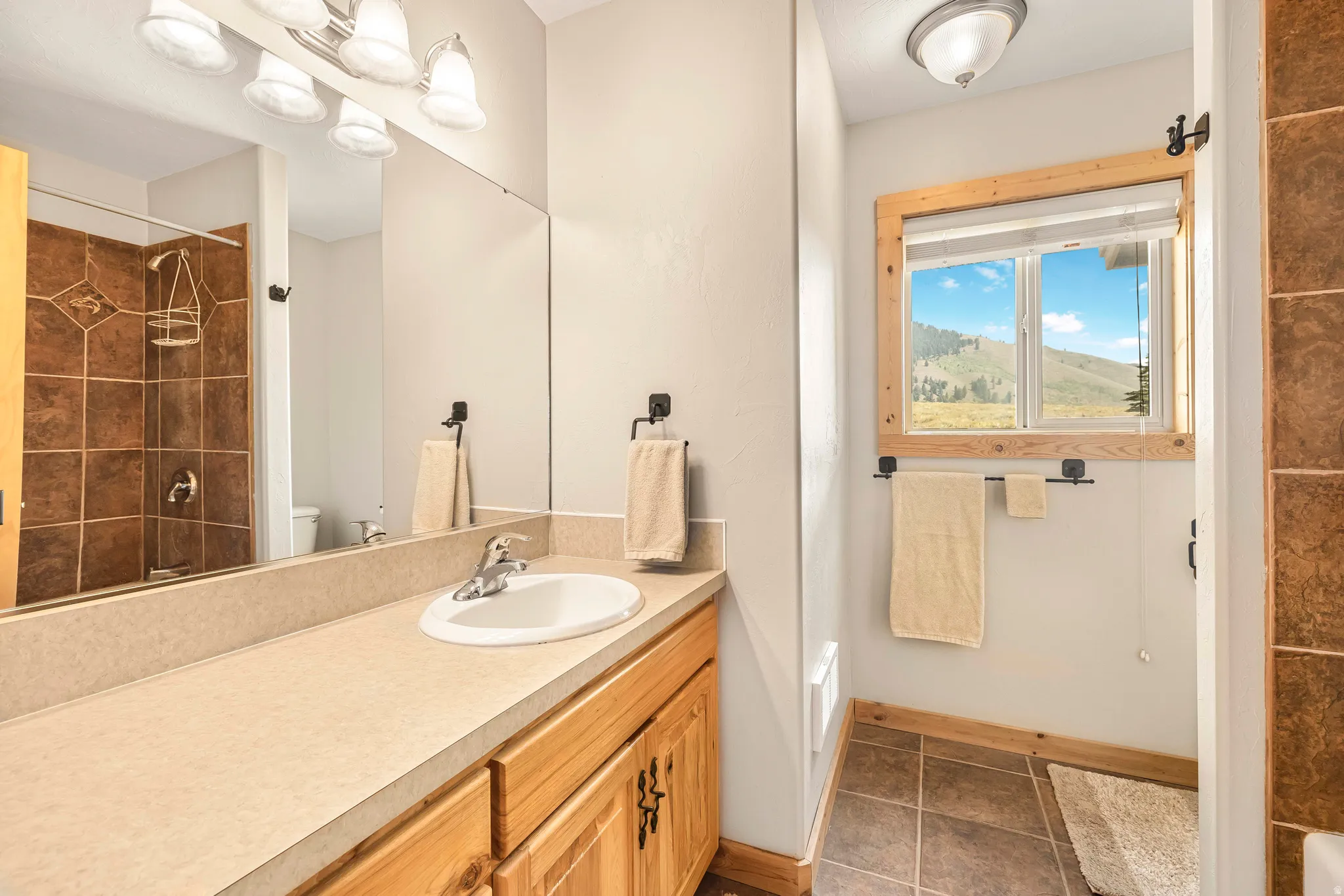 Full bathroom with vanity and dark tile patterned floors