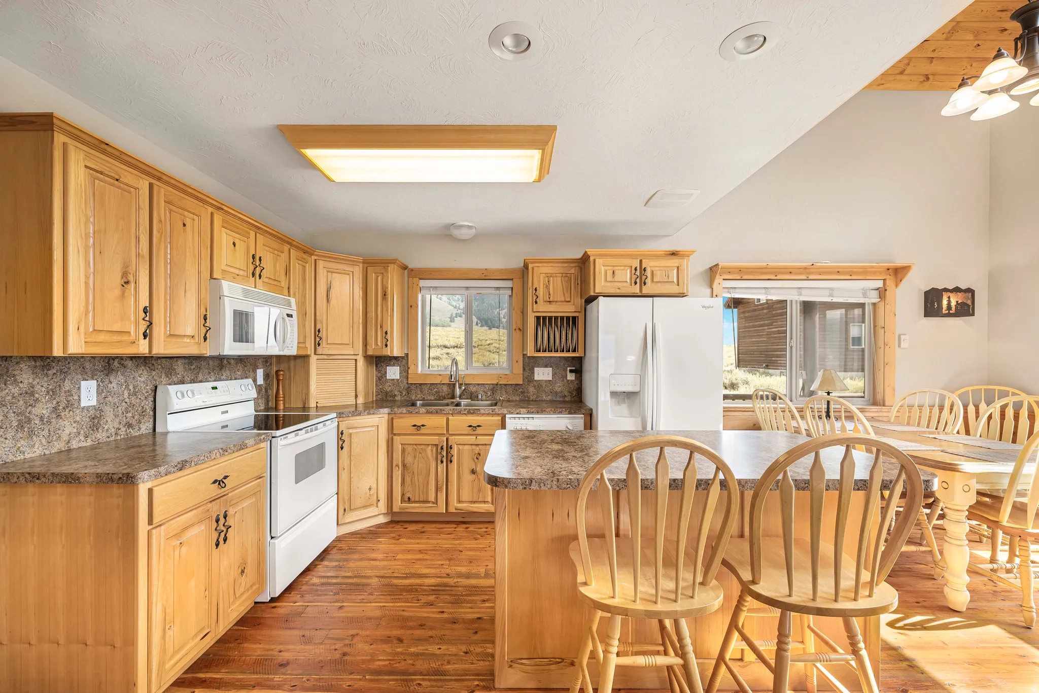 Kitchen featuring white appliances, tasteful backsplash, dark wood-style flooring, a kitchen breakfast bar, and lofted ceiling