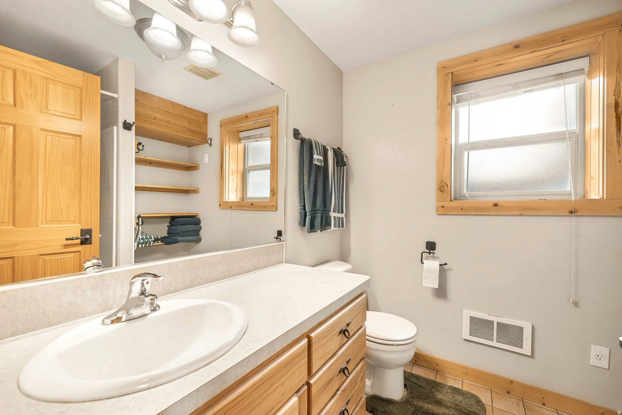 Bathroom featuring vanity, light tile patterned floors, and healthy amount of natural light