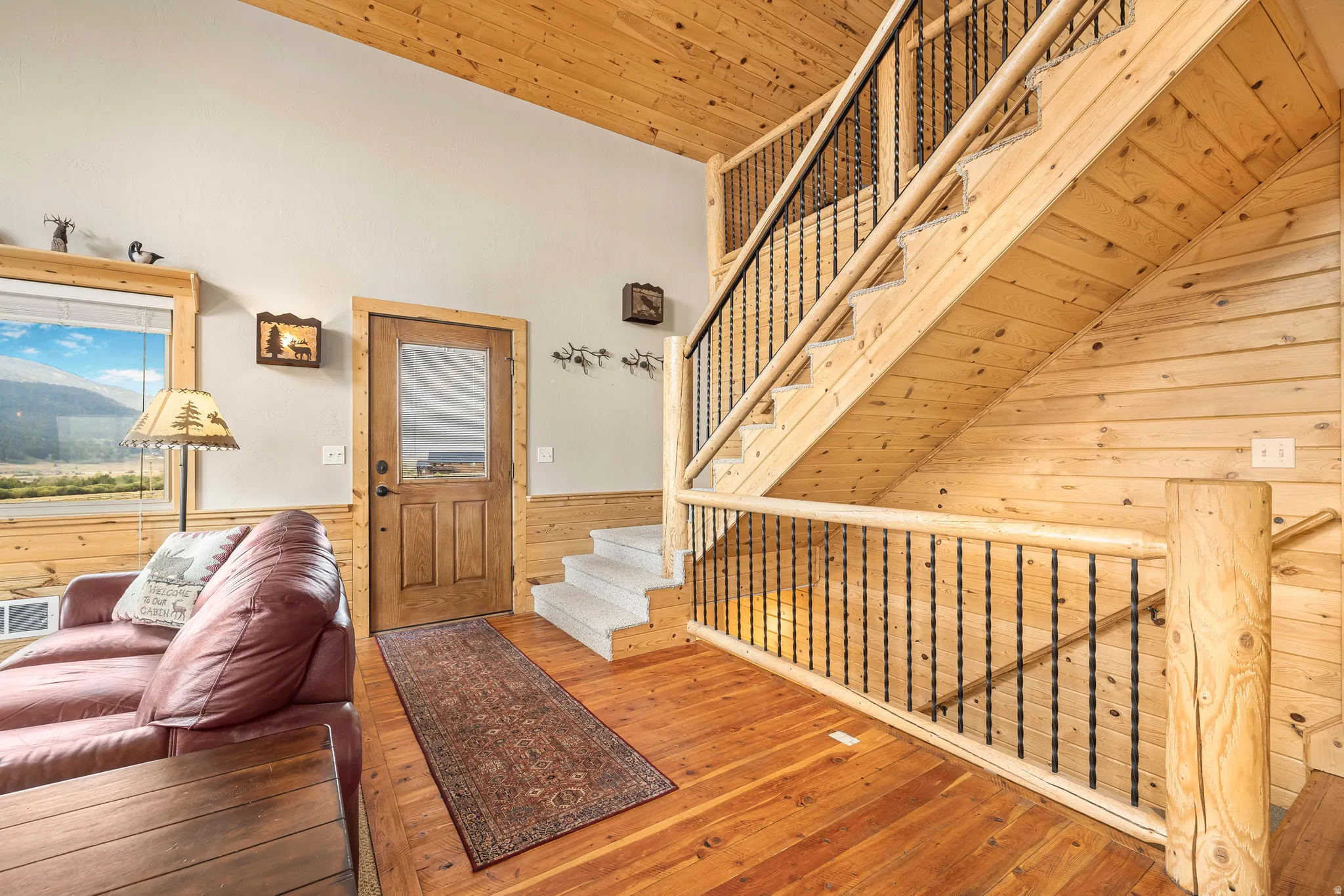 Foyer entrance with wood walls, stairs, wooden ceiling, hardwood / wood-style flooring, and wainscoting
