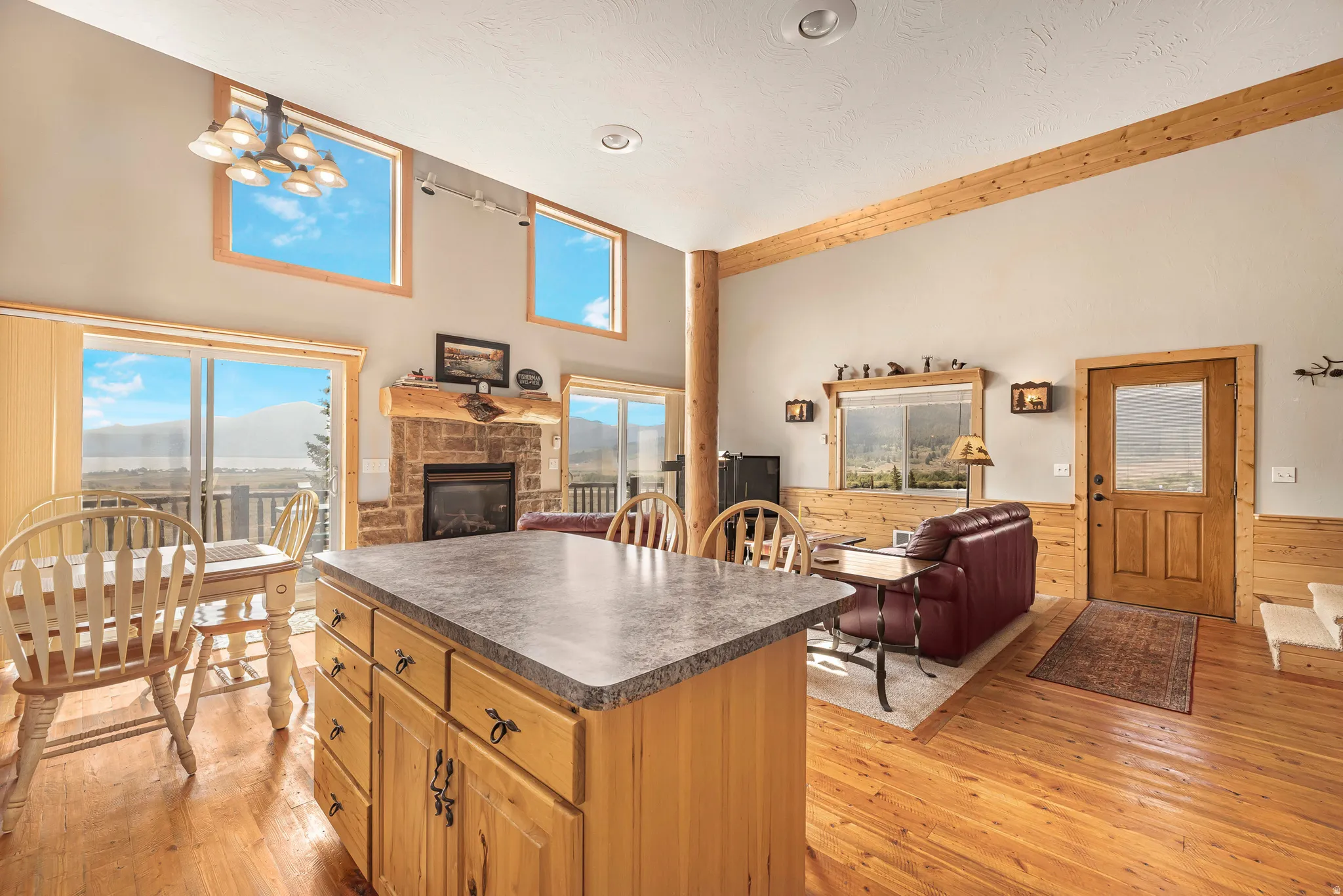 Kitchen with open floor plan, a fireplace, dark countertops, light wood-style flooring, and a towering ceiling