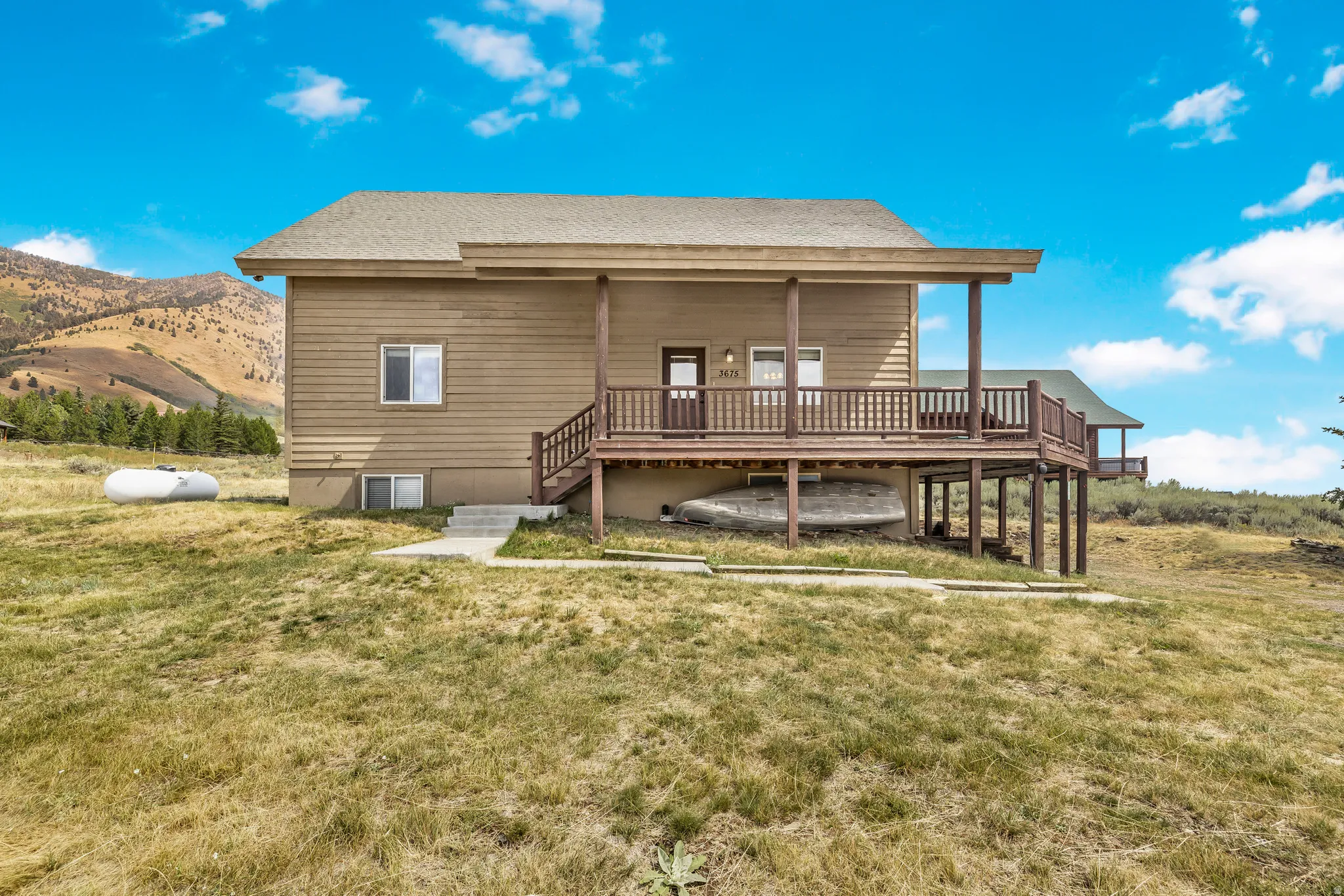Rear view of house with a lawn, a mountain view, and a shingled roof