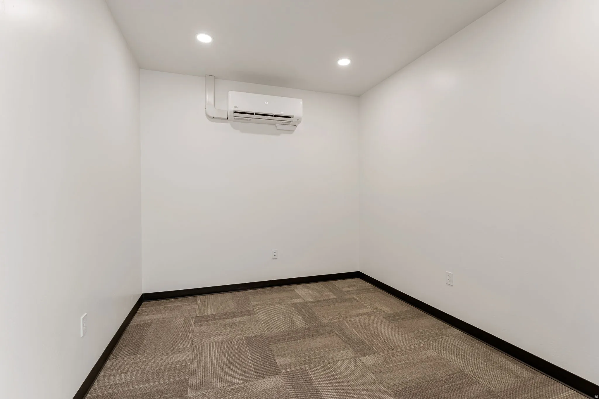 Unfurnished room with light carpet, recessed lighting, and an AC wall unit