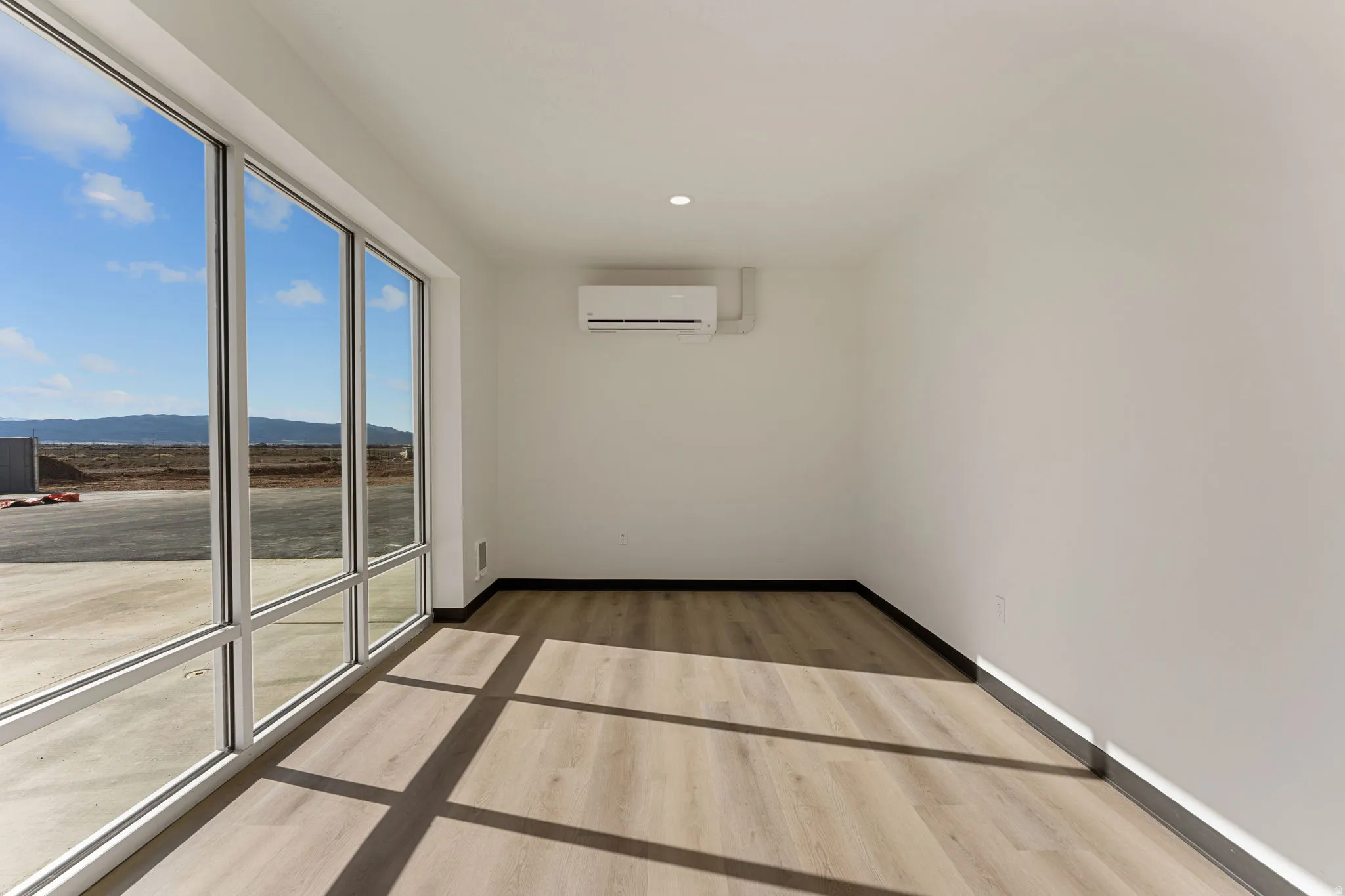 Unfurnished room with light wood finished floors, recessed lighting, a wall mounted AC, and a mountain view