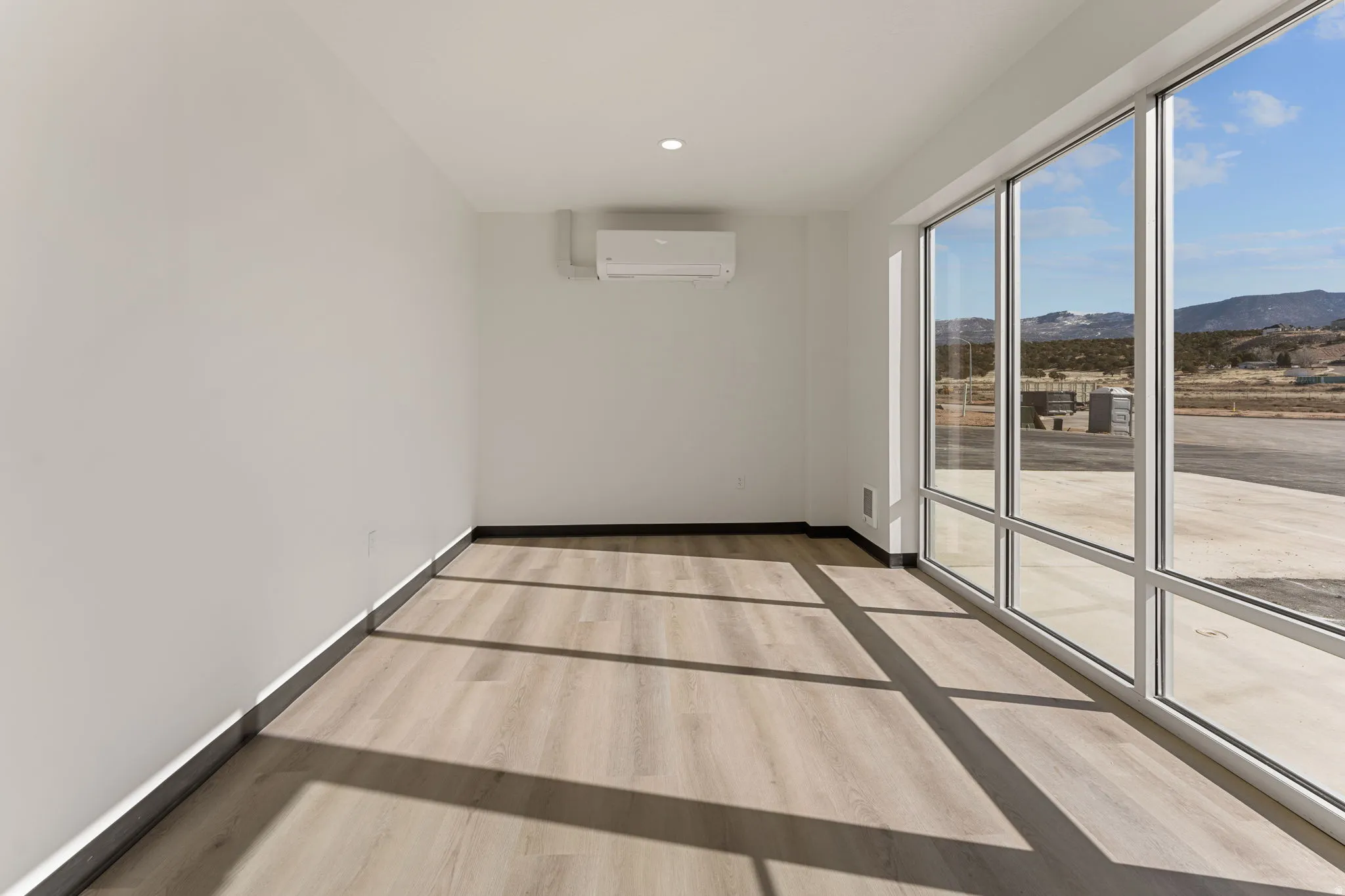 Spare room featuring light wood finished floors, a mountain view, recessed lighting, and an AC wall unit