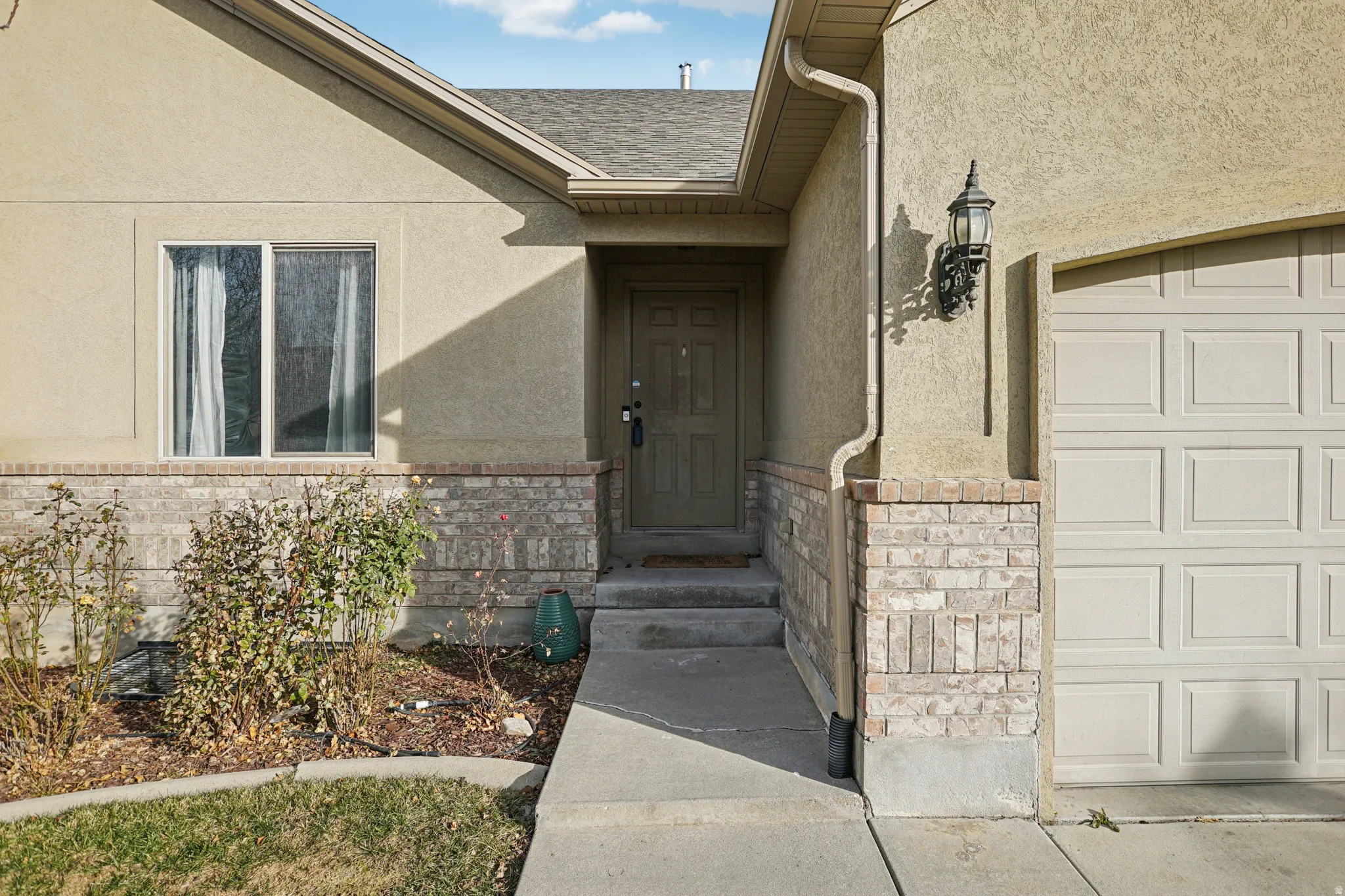 Doorway to property featuring stucco siding, stone siding, and a shingled roof