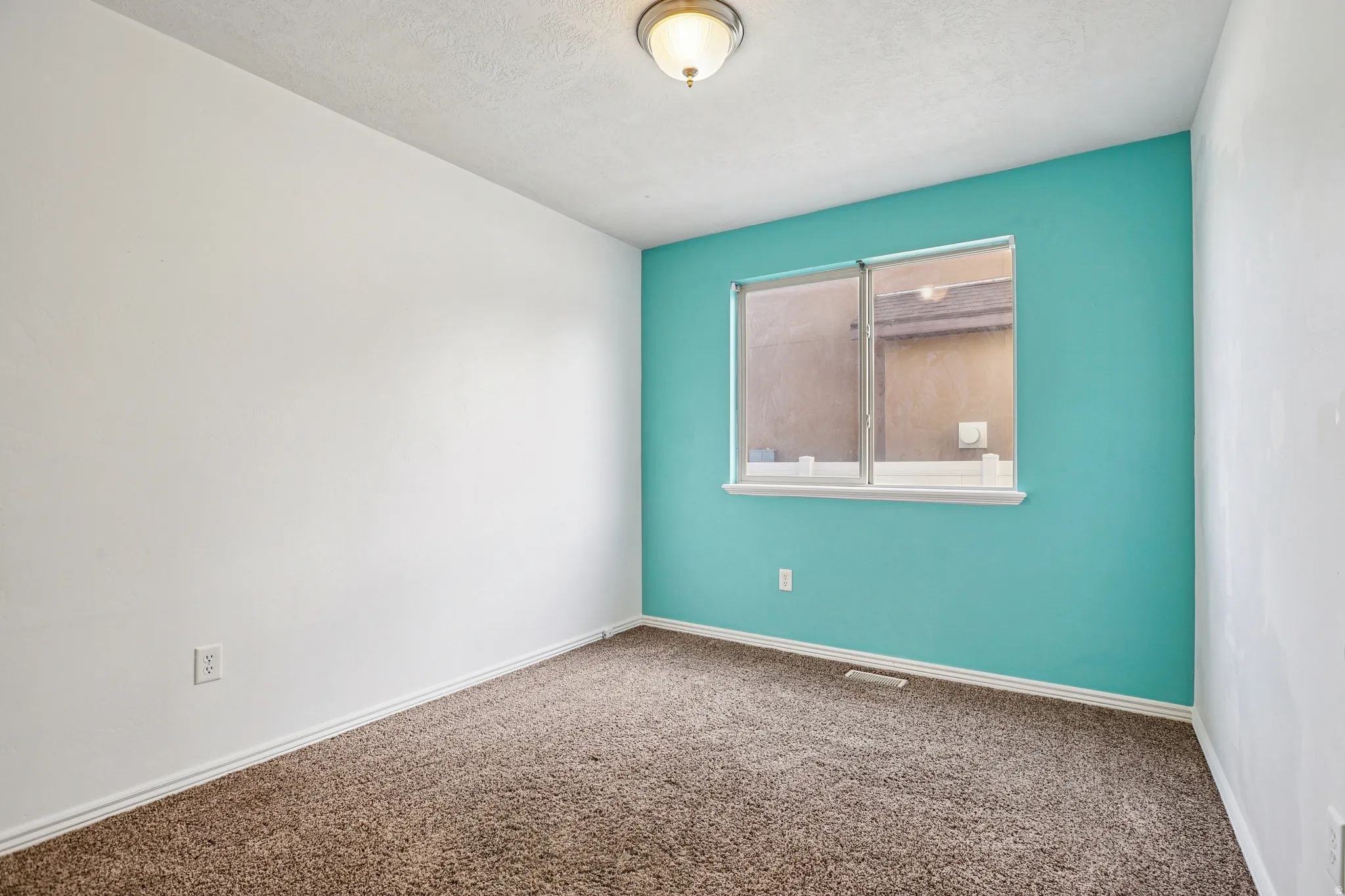 Carpeted spare room with baseboards and a textured ceiling