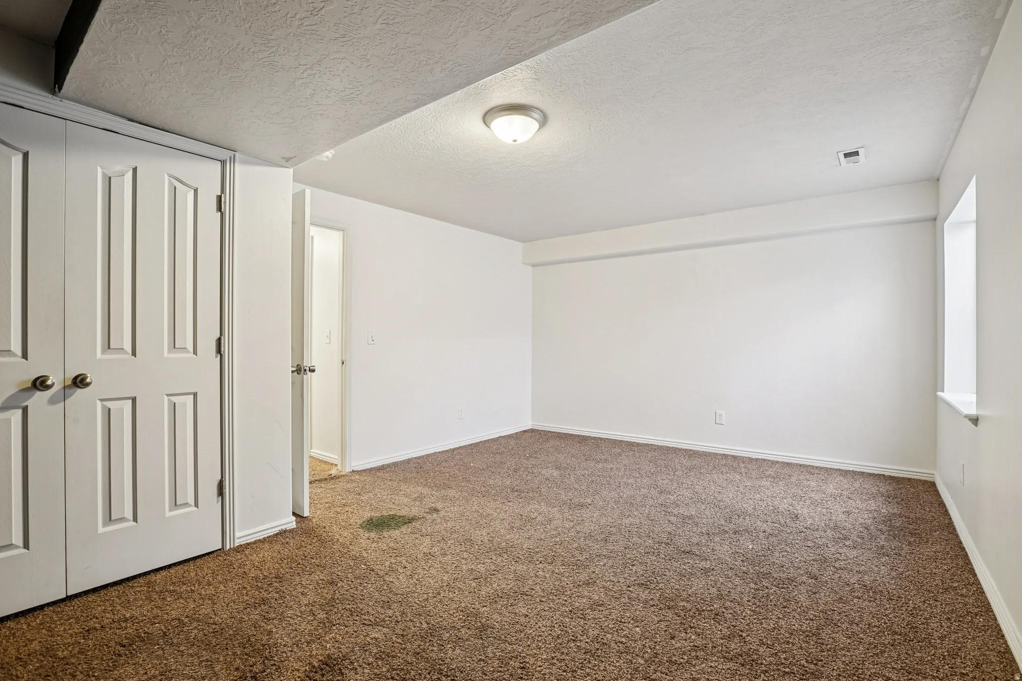 Unfurnished bedroom featuring carpet flooring, a textured ceiling, and a closet