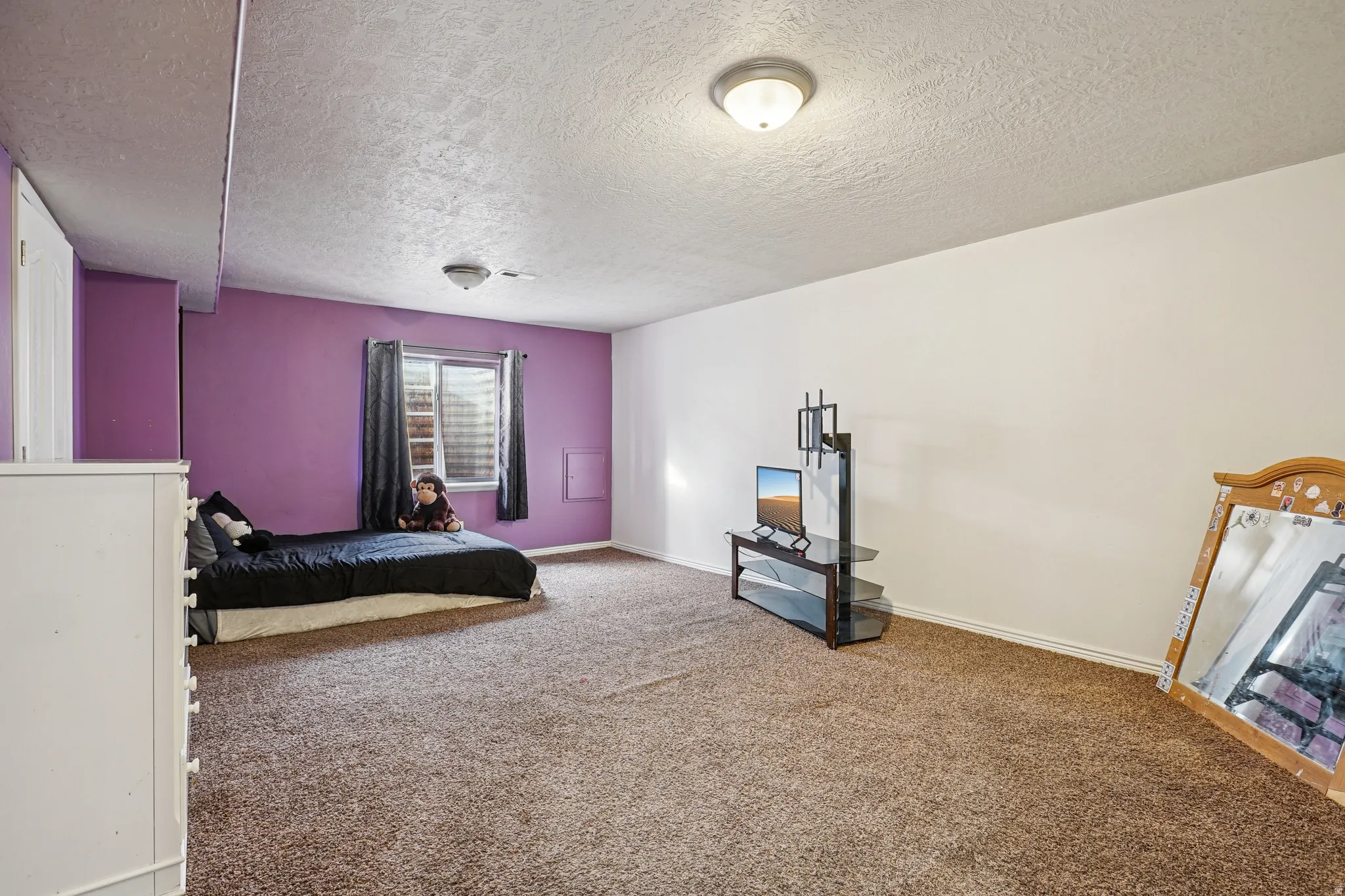 Carpeted bedroom featuring a textured ceiling and baseboards