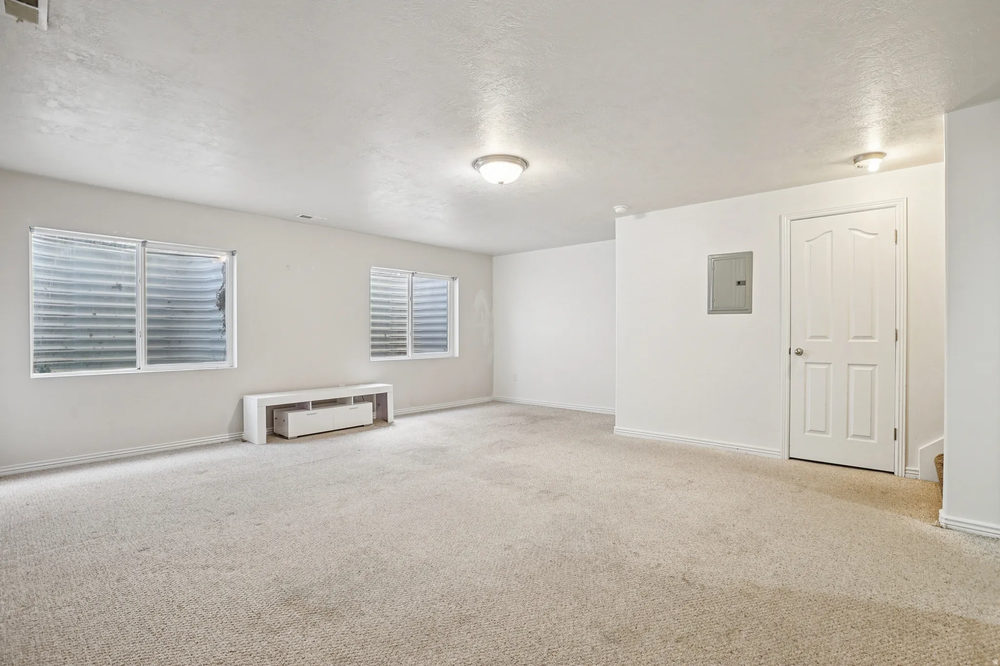 Unfurnished room with light carpet, a textured ceiling, and electric panel