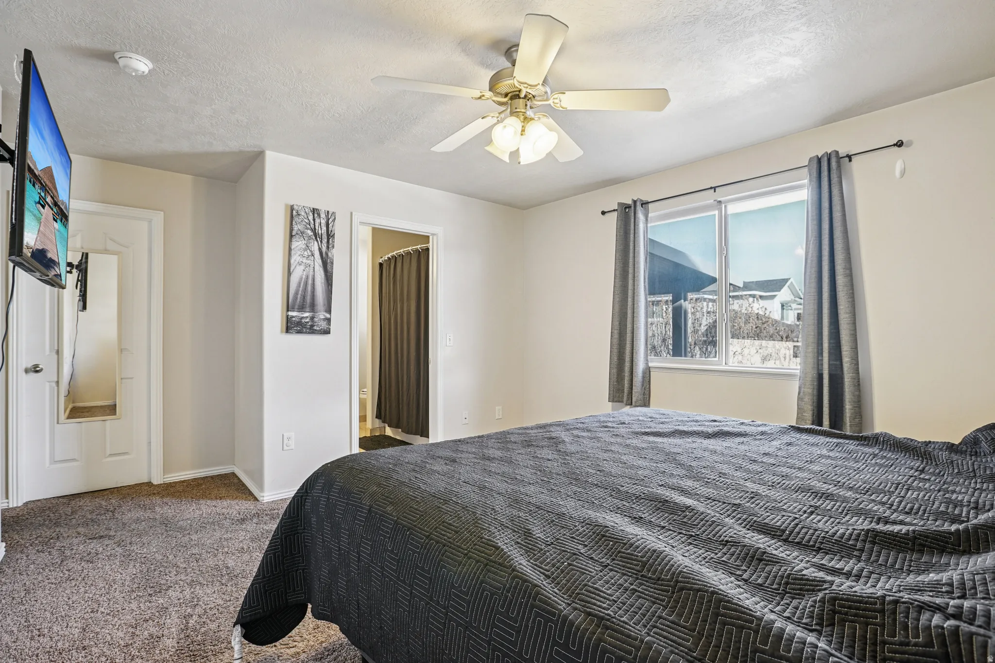 Carpeted bedroom featuring a textured ceiling, a ceiling fan, and connected bathroom