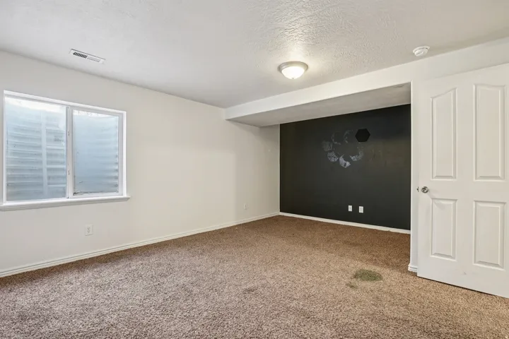 Unfurnished room with a textured ceiling and carpet flooring
