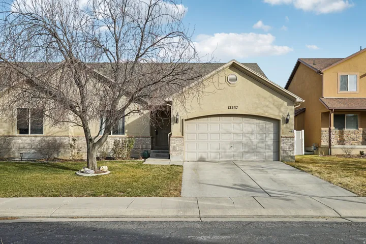View of front of house featuring a front yard, concrete driveway, stucco siding, and an attached garage