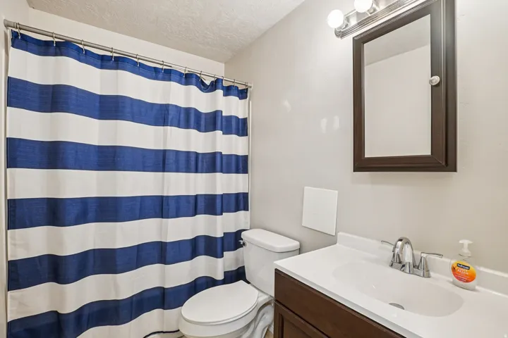 Full bathroom with vanity, a shower with curtain, and a textured ceiling