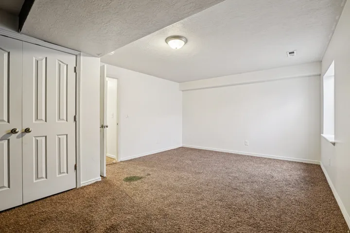 Unfurnished bedroom featuring carpet flooring, a textured ceiling, and a closet