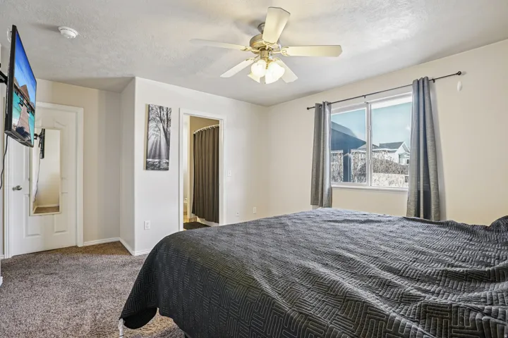 Carpeted bedroom featuring a textured ceiling, a ceiling fan, and connected bathroom