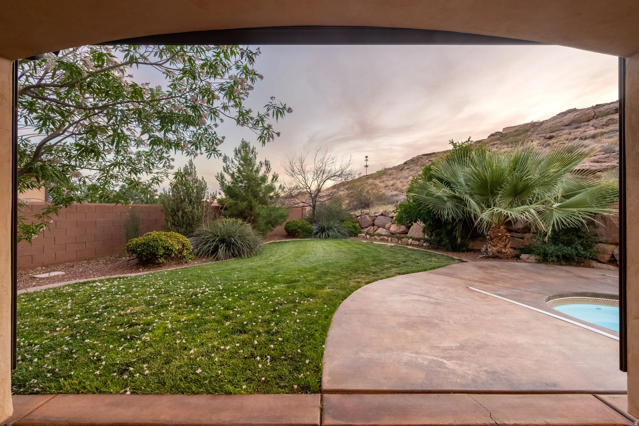 Yard at dusk with a fenced backyard, a mountain view, and a patio