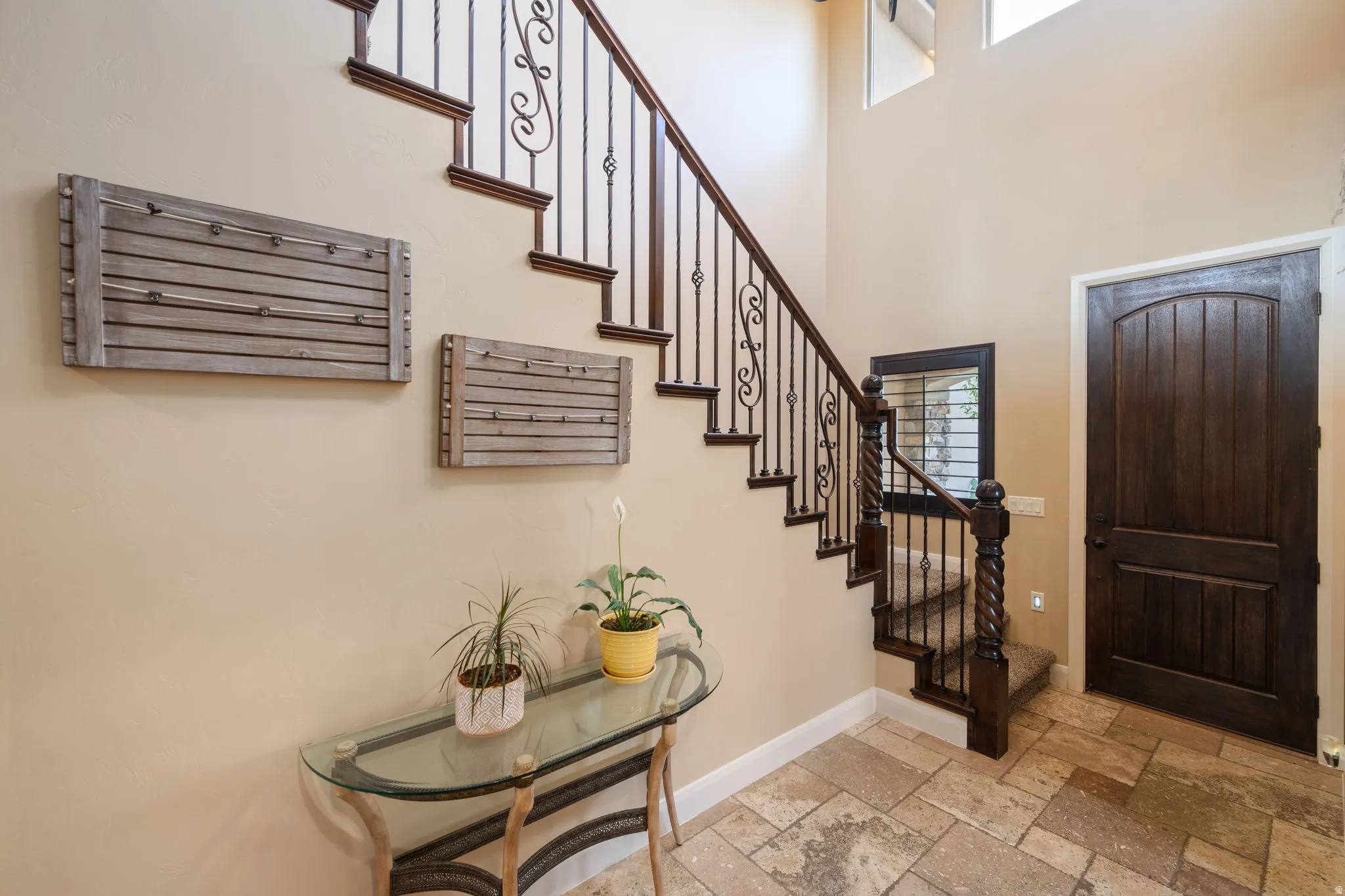 Foyer featuring stone tile flooring, a towering ceiling, and stairs