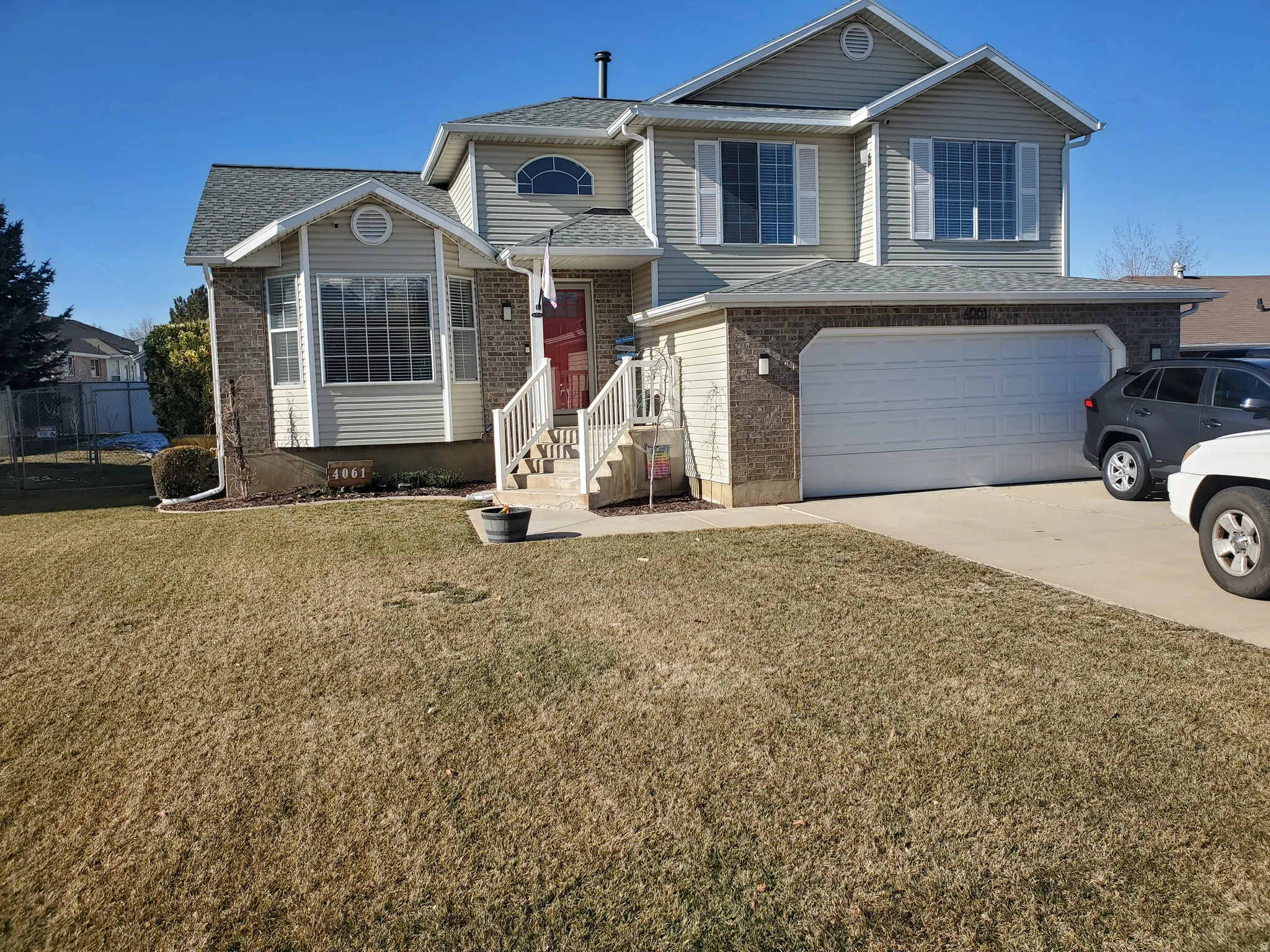 Tri-level home featuring an attached garage, concrete driveway, brick siding, and roof with shingles