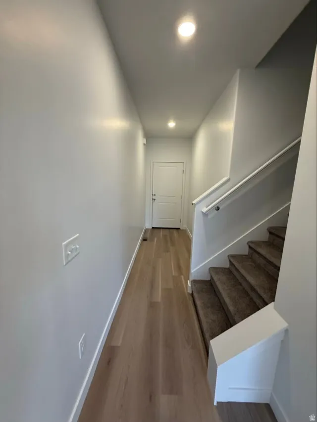 Hall featuring light wood finished floors, recessed lighting, and stairs