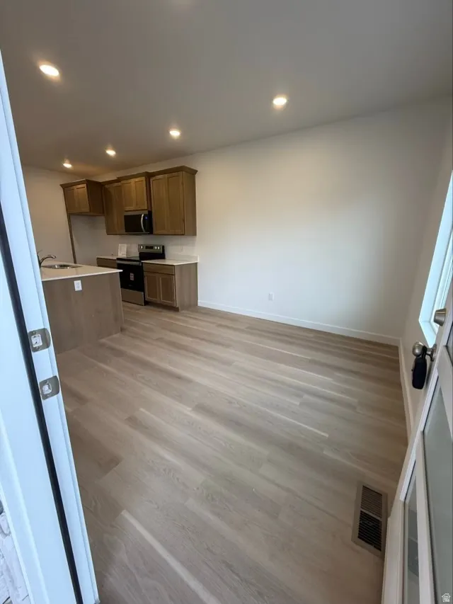Kitchen with appliances with stainless steel finishes, light countertops, light wood-style floors, recessed lighting, and brown cabinetry