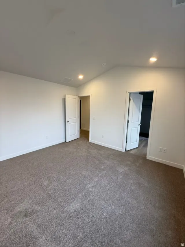 Unfurnished bedroom featuring carpet floors, recessed lighting, and vaulted ceiling