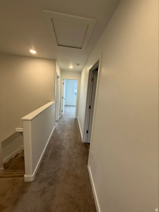 Corridor featuring an upstairs landing, dark carpet, and recessed lighting