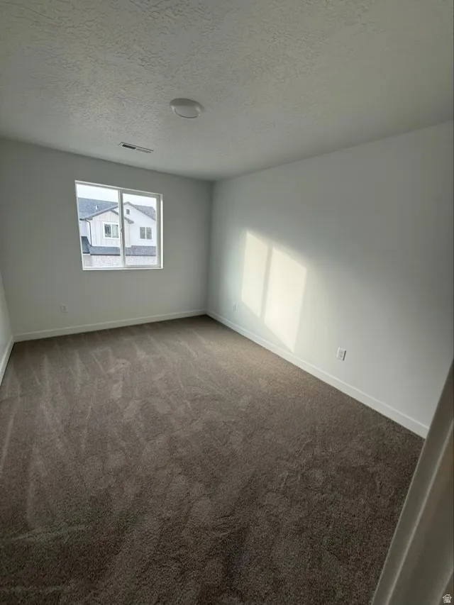 Spare room featuring light colored carpet and a textured ceiling