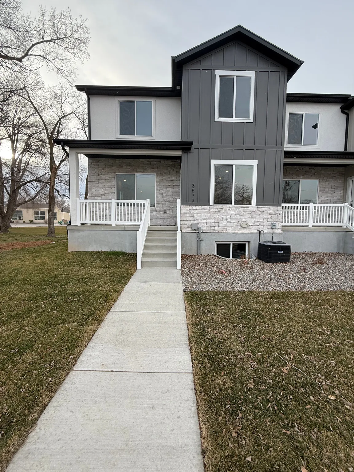 View of front facade featuring a front yard, stone siding, board and batten siding, and covered porch