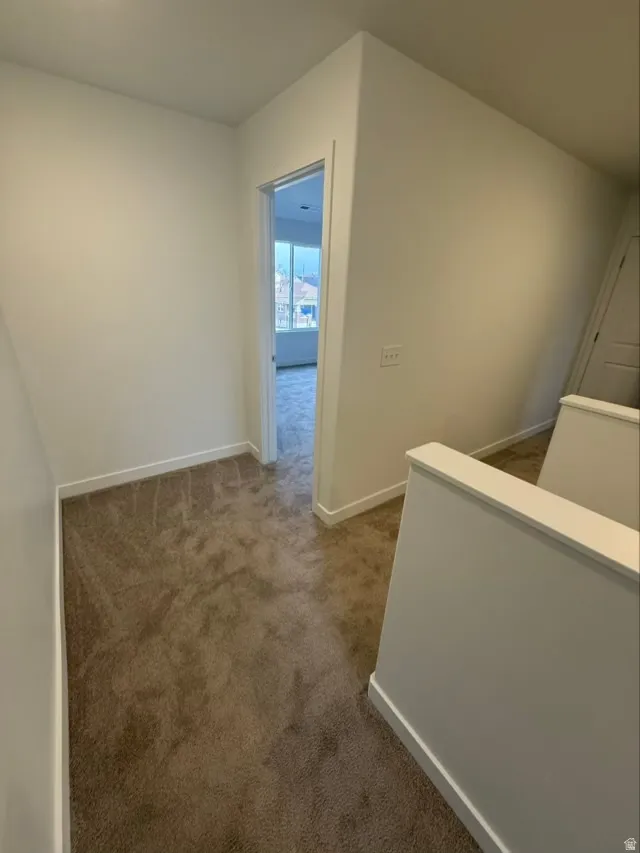 Hallway with an upstairs landing and dark carpet