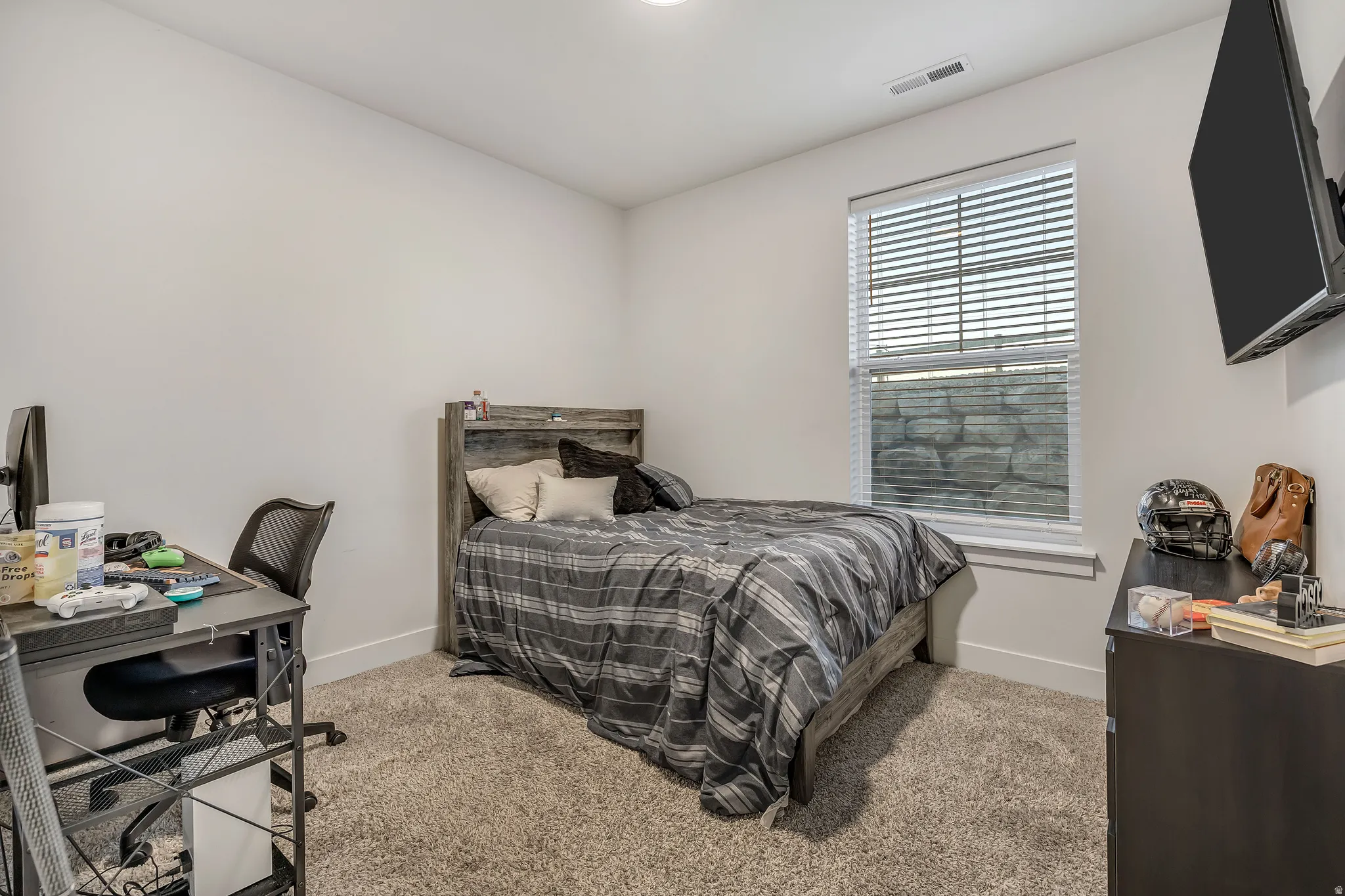 Bedroom with light colored carpet and an office area