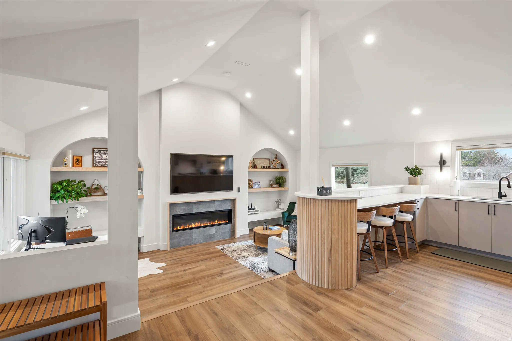 Kitchen with a kitchen bar, built in shelves, a peninsula, light wood-style floors, and a tile fireplace