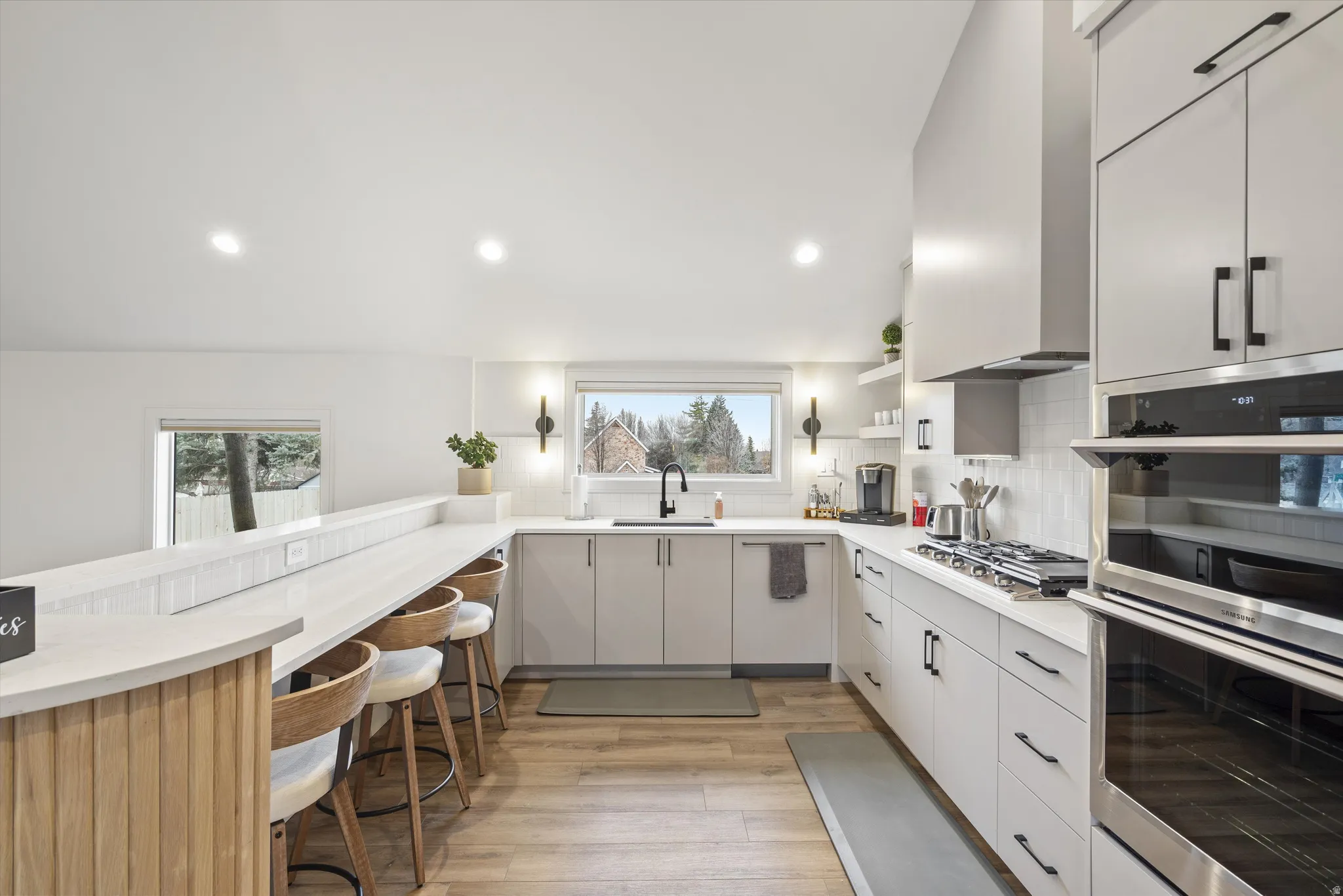 Kitchen with stainless steel appliances, a breakfast bar area, open shelves, a peninsula, and light wood-style floors
