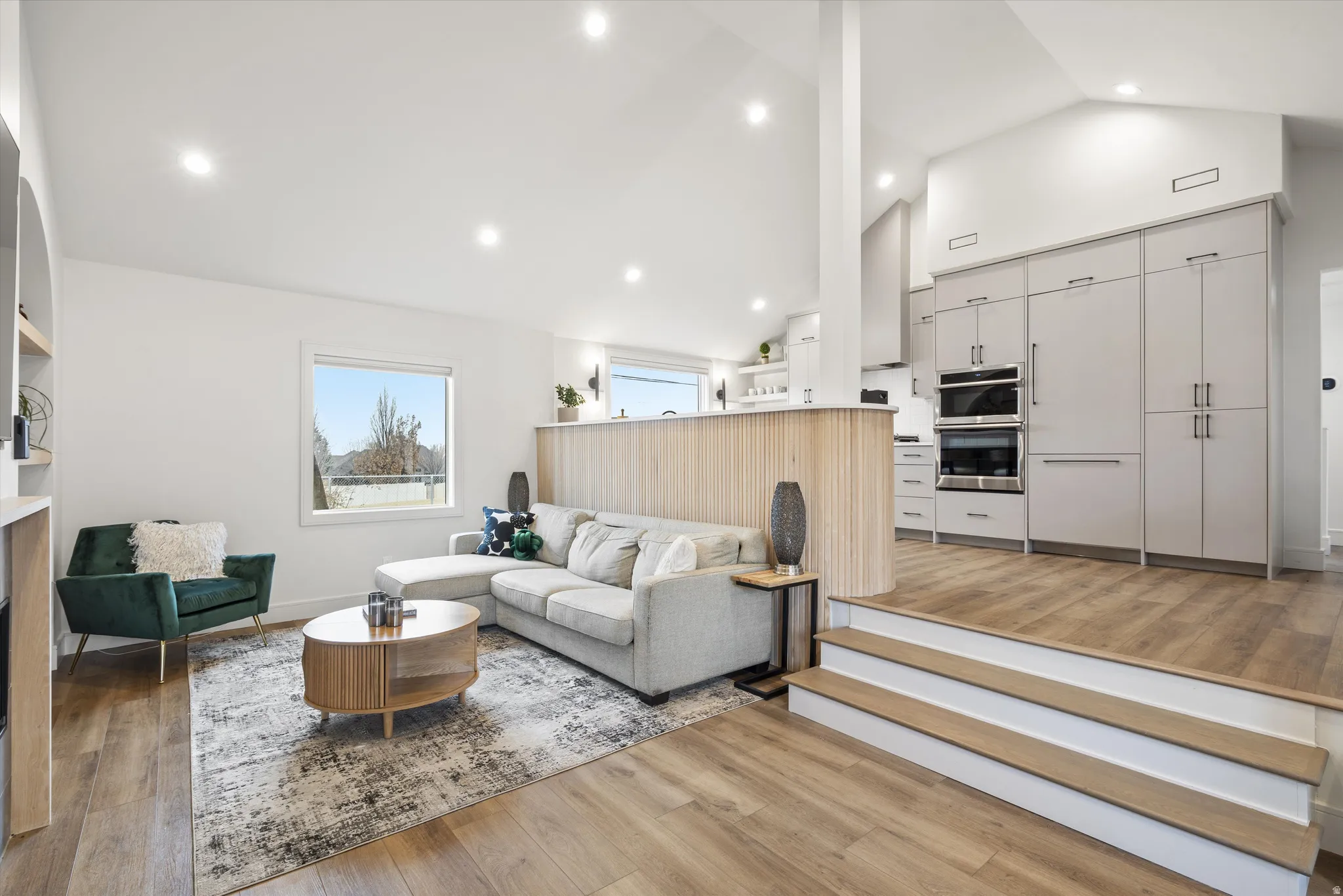 Living room featuring light wood-type flooring, high vaulted ceiling, and recessed lighting